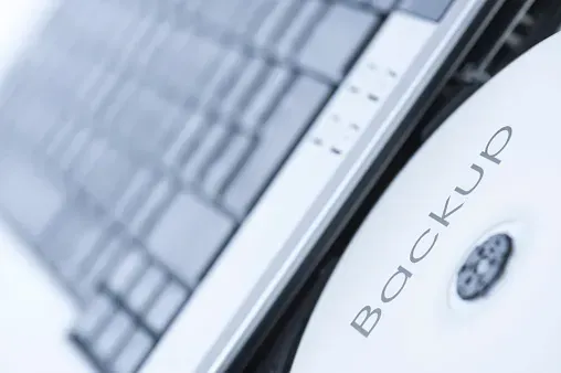 A backup cd is sitting on top of a laptop keyboard A backup cd is sitting on top of a laptop keyboard