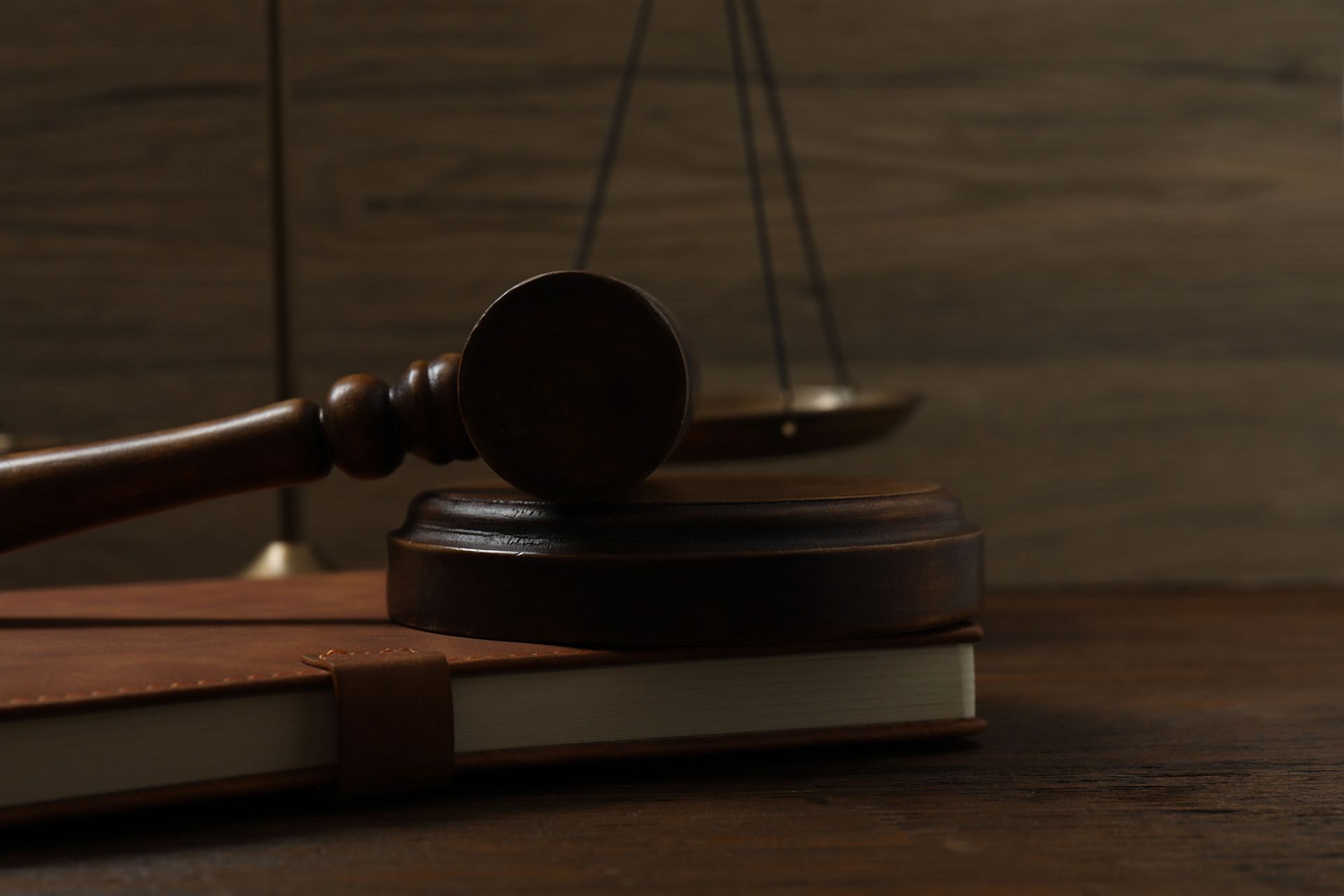 Pen law book, judge's gavel, scales, handcuffs on table in courtroom or law enforcement office.