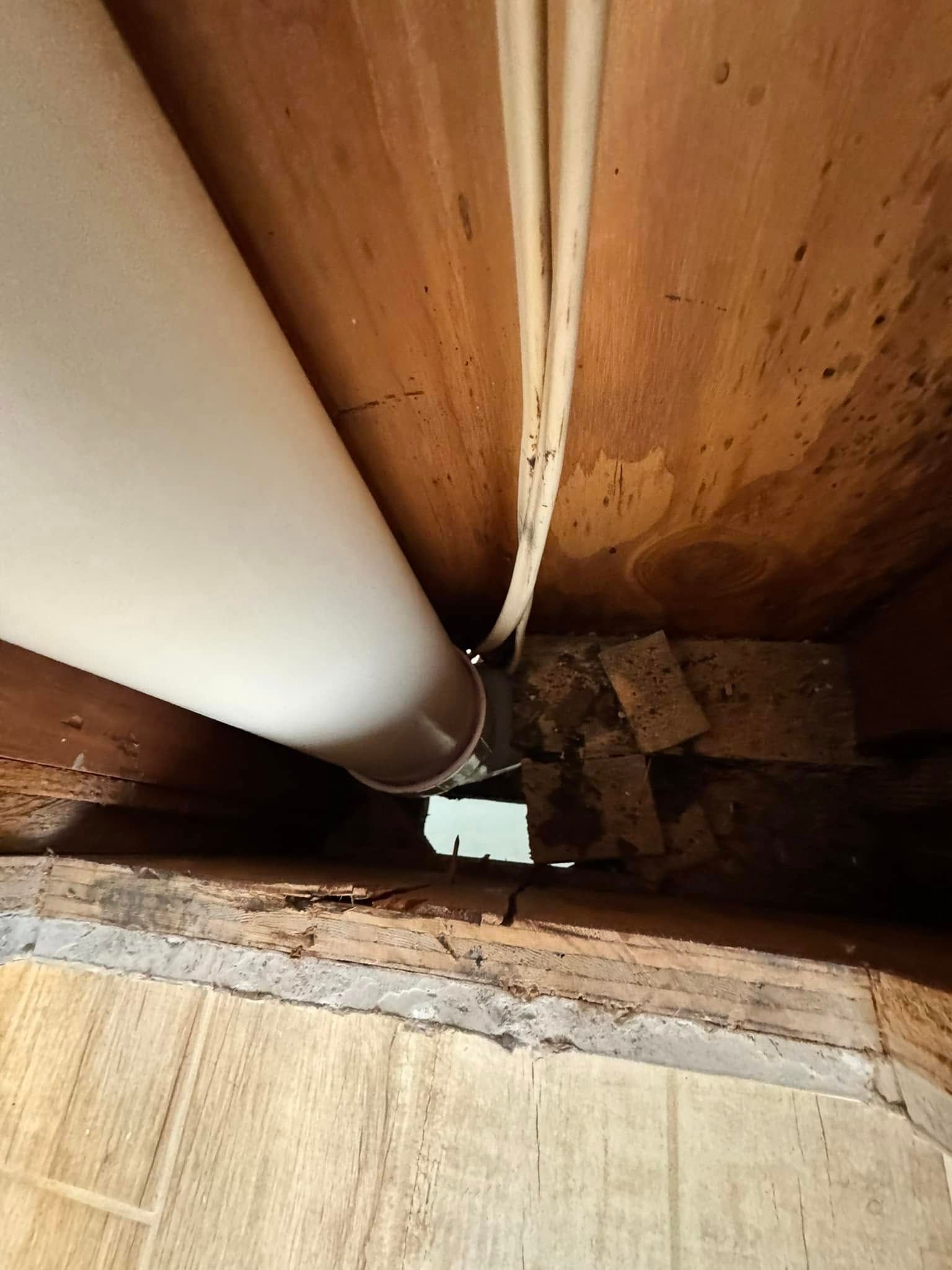 White pipe and electrical wires running through wooden framing.