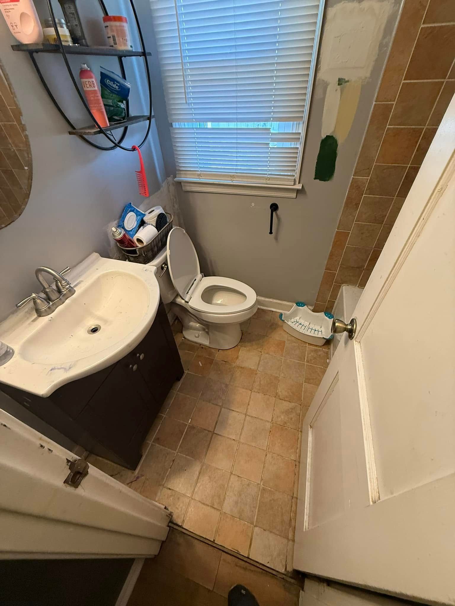 Small bathroom with sink, toilet, window, and brown tiled floor.
