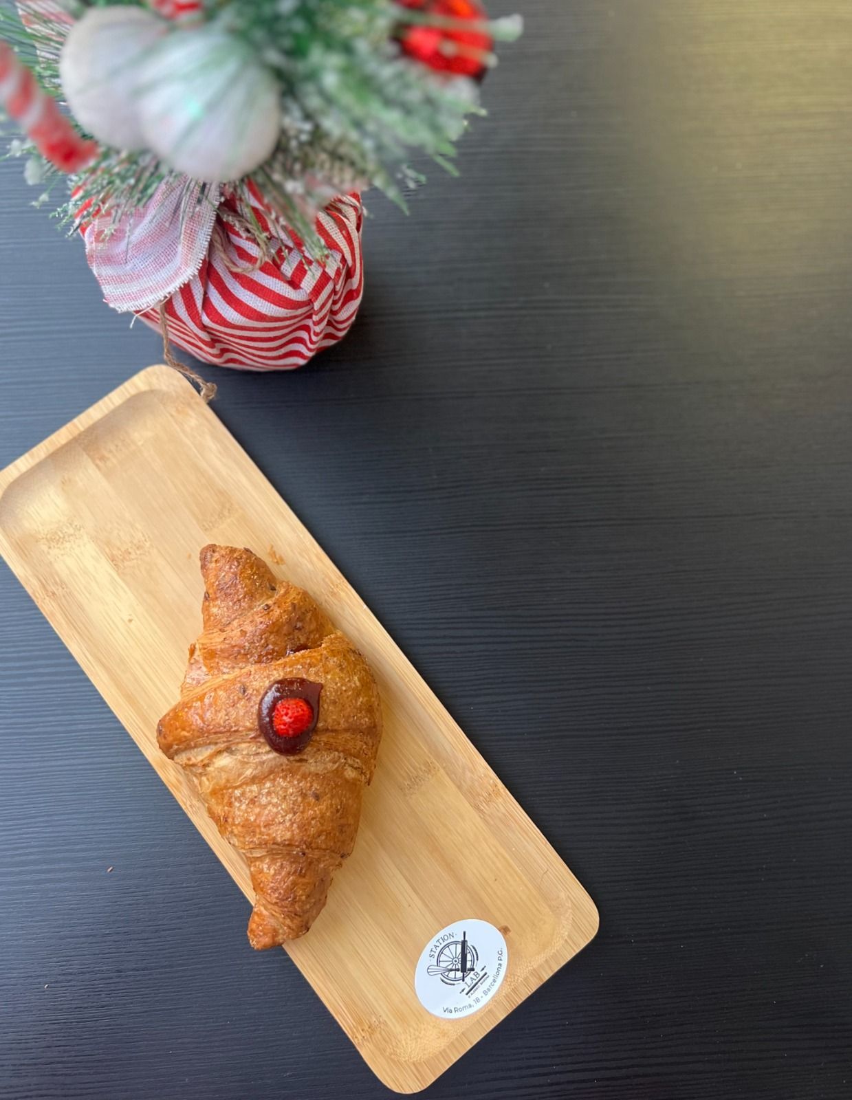 un croissant con una ciliegia su di esso è su un vassoio di legno .