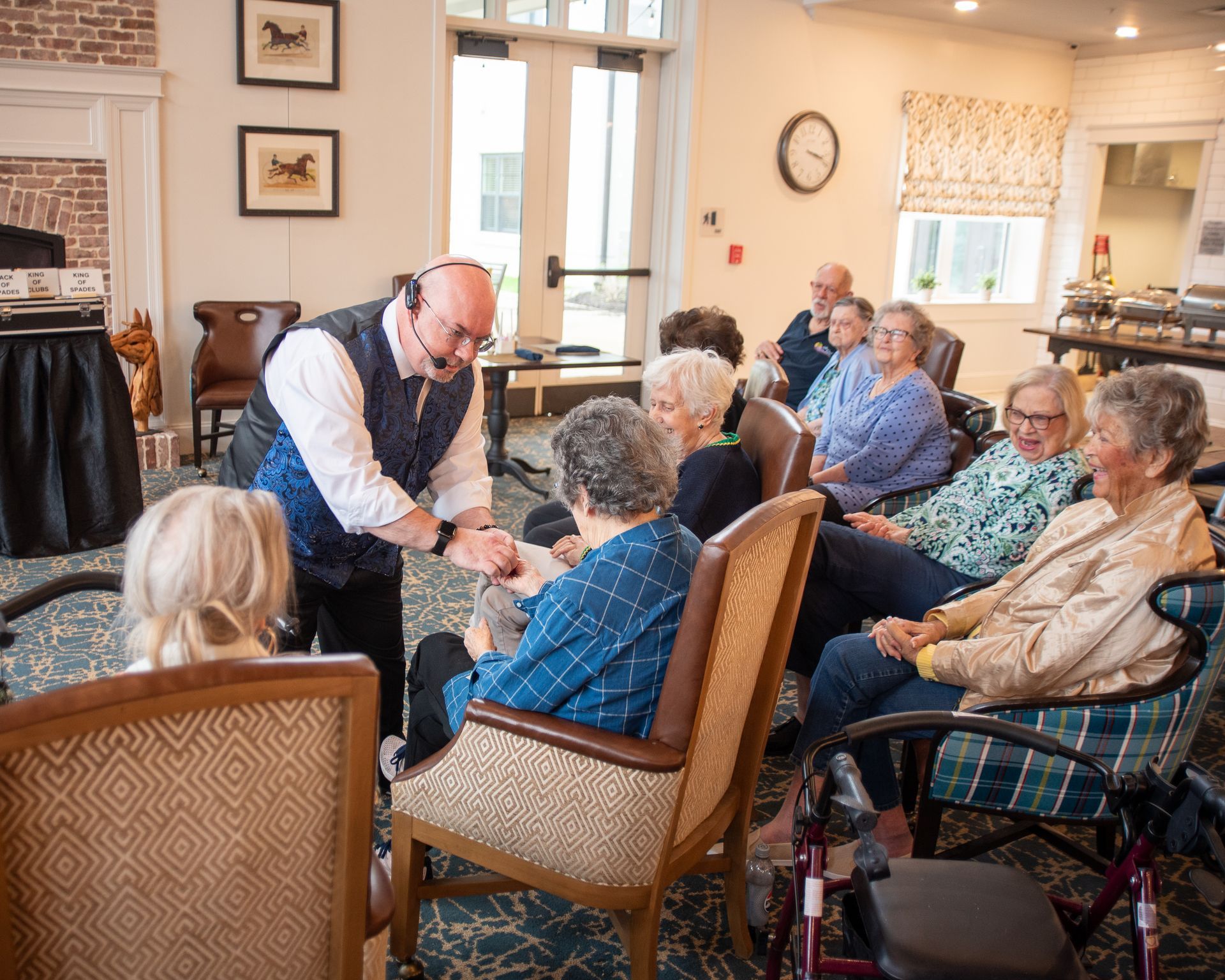 A group of elderly people are sitting in chairs watching a man perform a trick