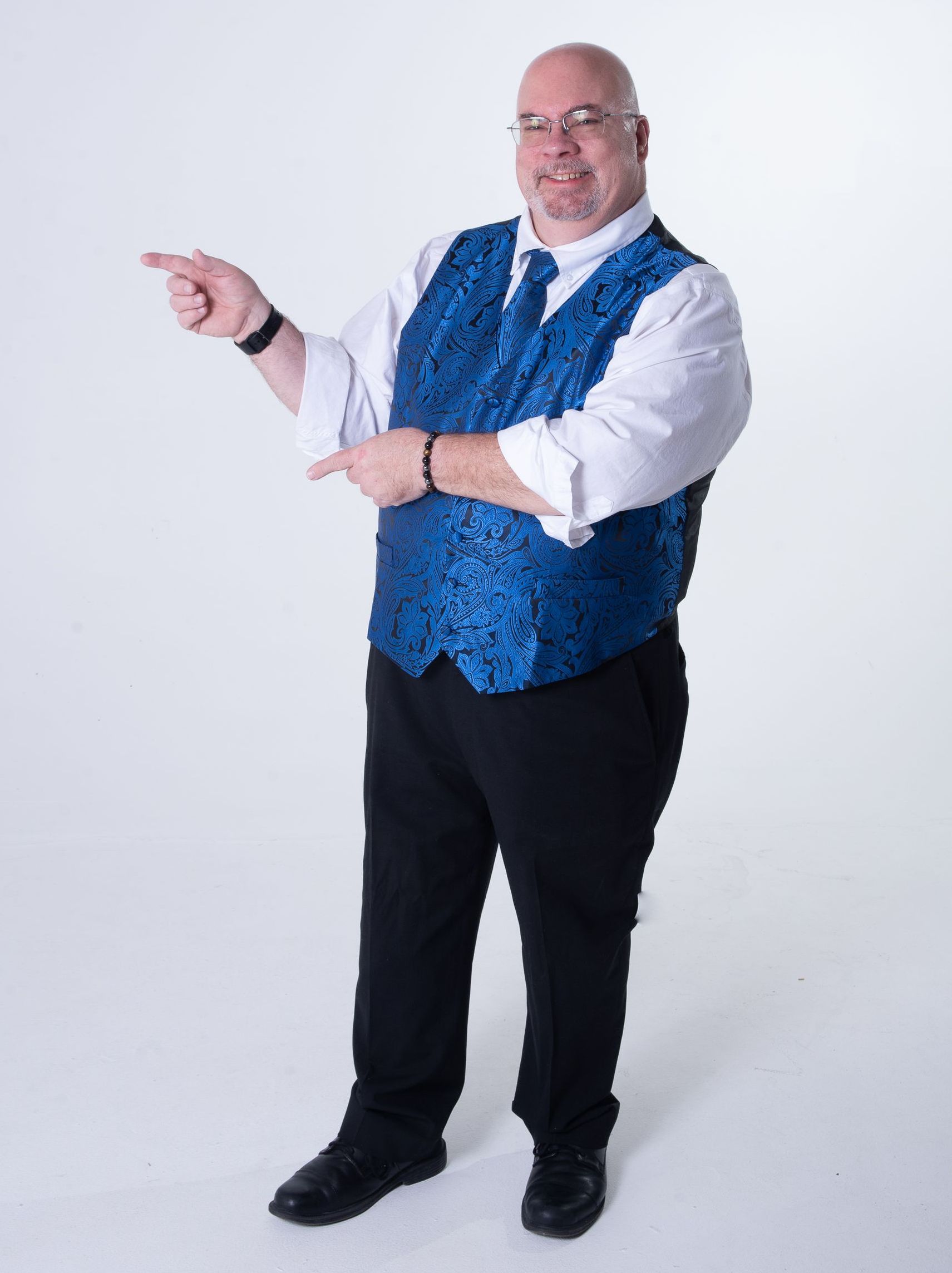 A man wearing a blue vest and black pants is pointing