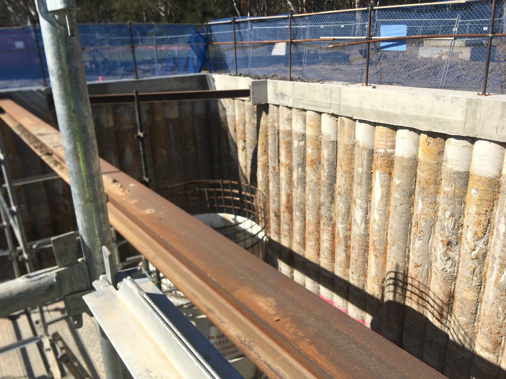 A large metal beam is sitting in front of a concrete wall.