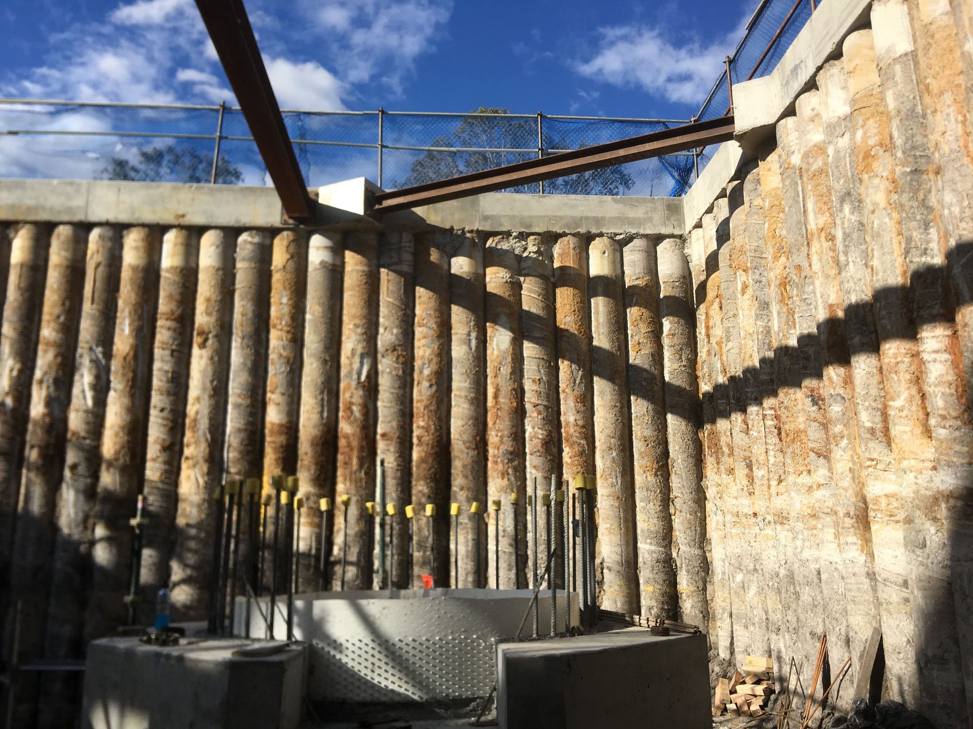 A fence made of wooden poles is being built on a construction site.