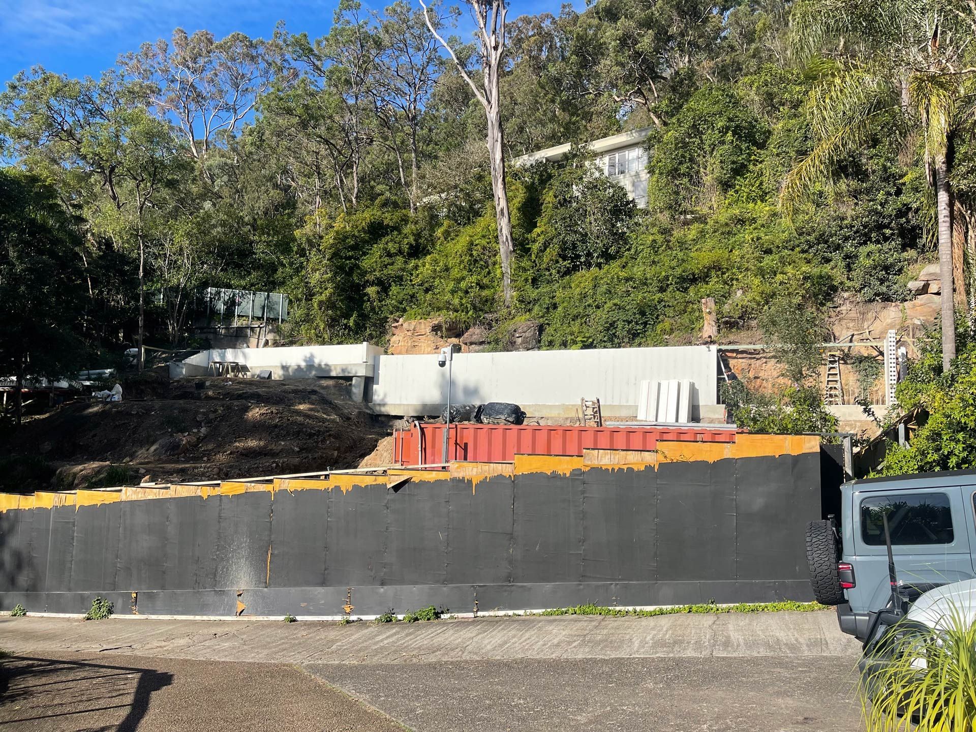 A white truck is parked on the side of the road next to a black fence.