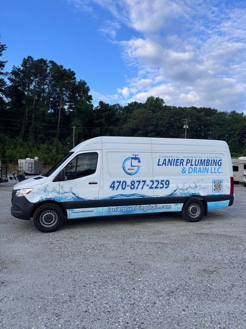 Three people in blue shirts stand in front of a white van advertising Lanier Plumbing.