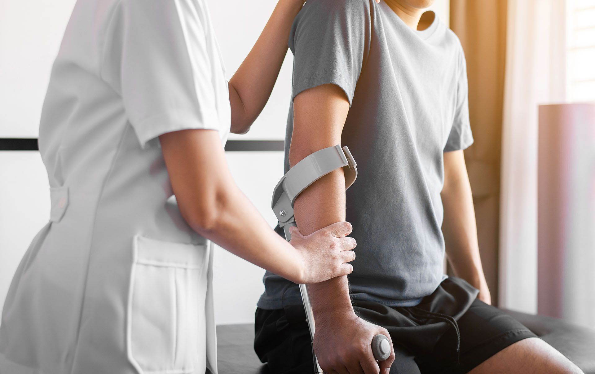 A nurse is helping a patient with a cane.