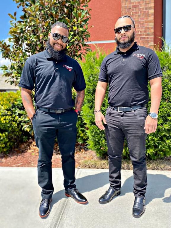 Two men are standing next to each other on a sidewalk.