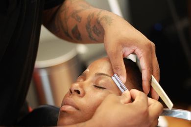 A man is shaving a woman 's eyebrows with a razor.