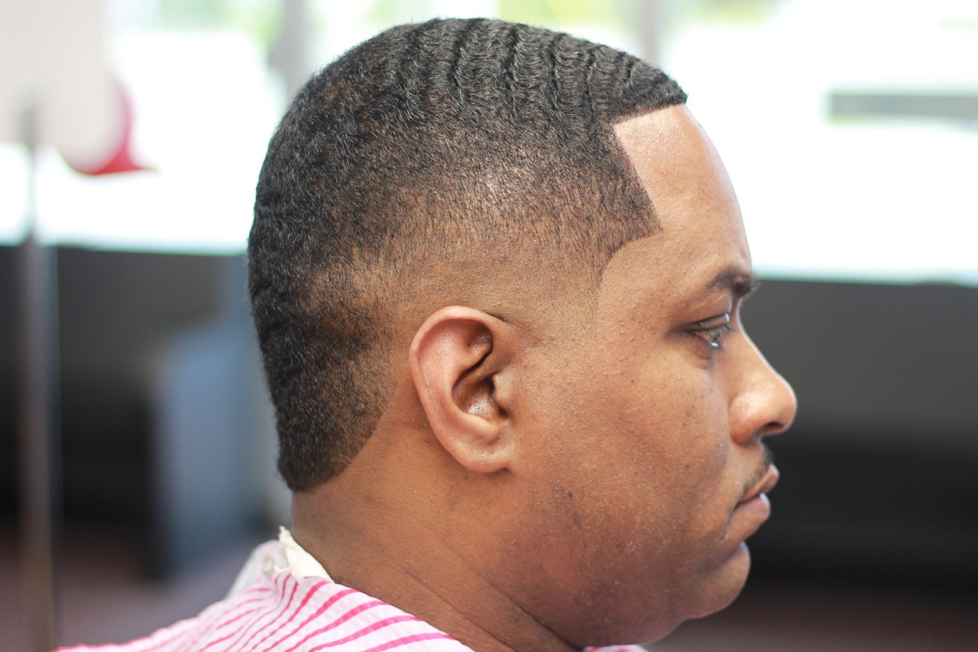 A man is getting his hair cut at a barber shop.