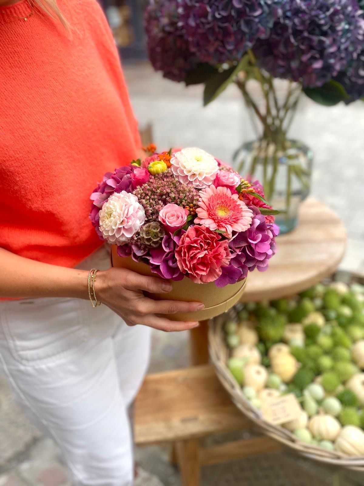 Une boîte remplie de fleurs est posée sur une table en bois.