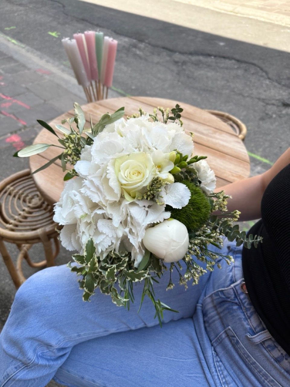 Une femme est assise à une table tenant un bouquet de fleurs blanches.