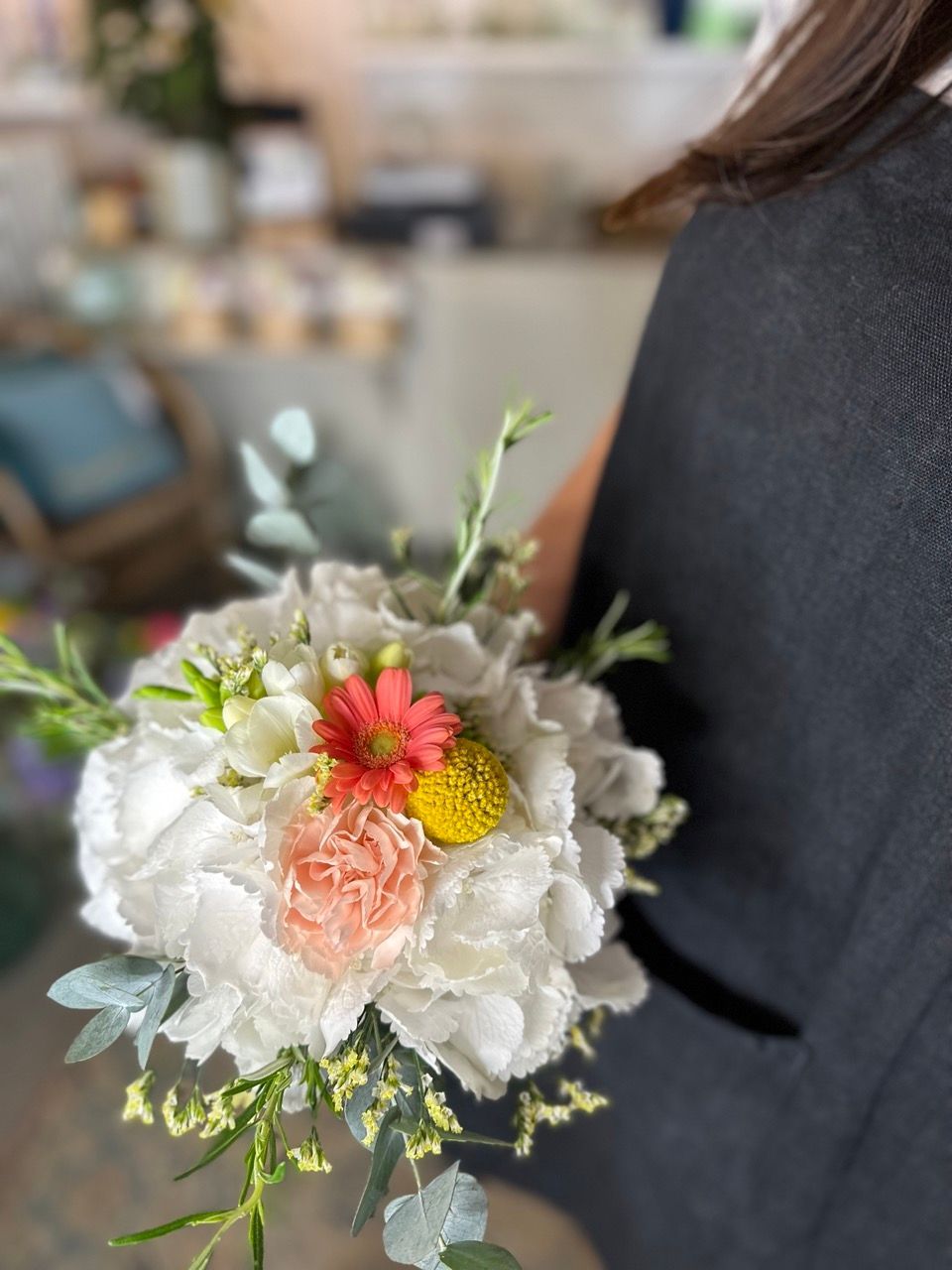 Une femme tient un bouquet de fleurs dans sa main.