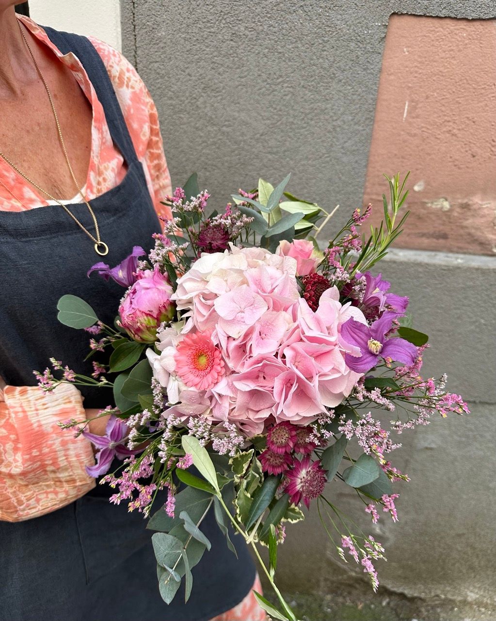 Une femme tient un bouquet de fleurs roses et violettes