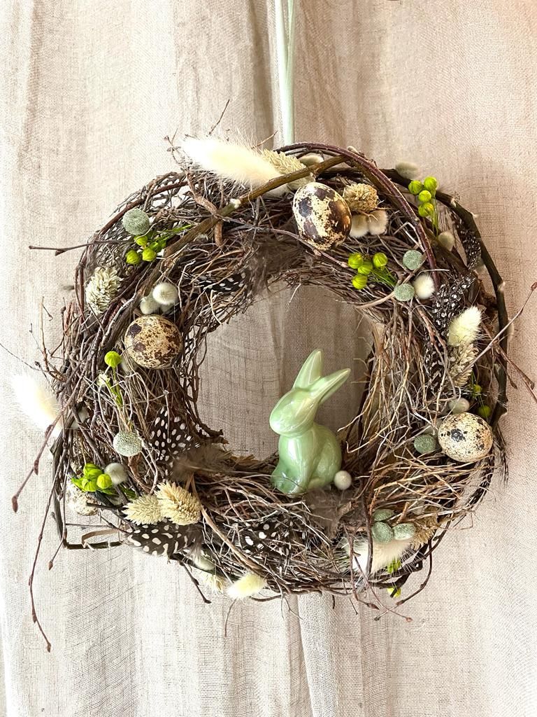 Une couronne avec un lapin vert au milieu est accrochée au mur.