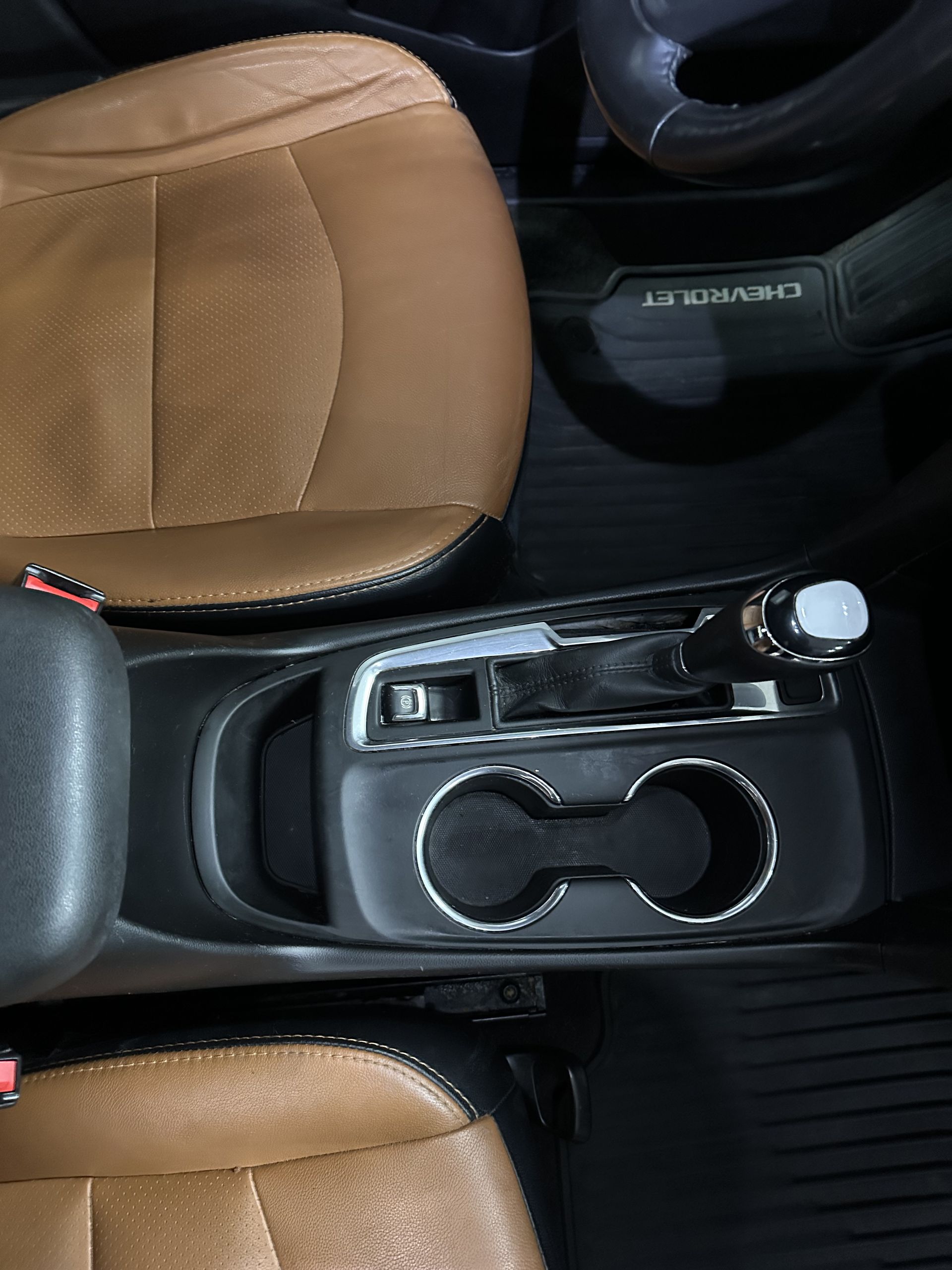 Overhead view of a car interior with brown leather seats, a gear shifter, and two cup holders.