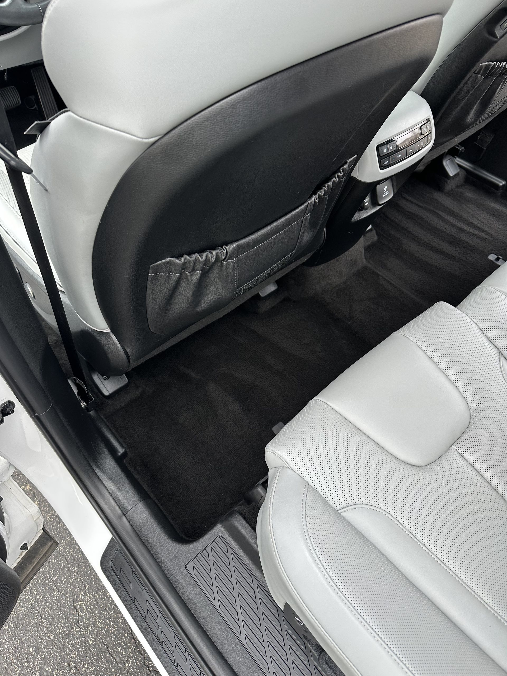 Back seat interior of a car with light gray patterned seats and dark gray carpeting.
