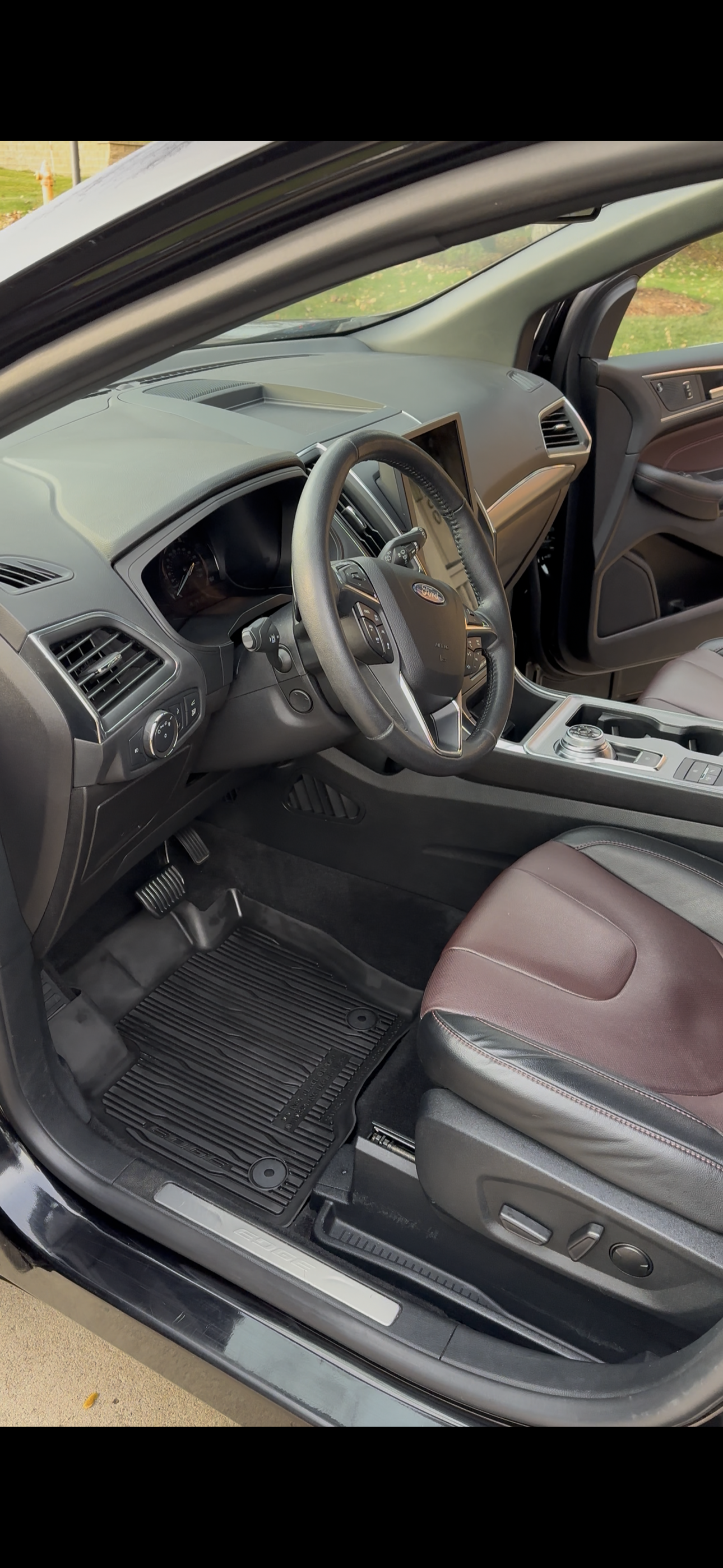 Interior view of a modern car with a black steering wheel, dark dashboard, and brown-trimmed leather seats.