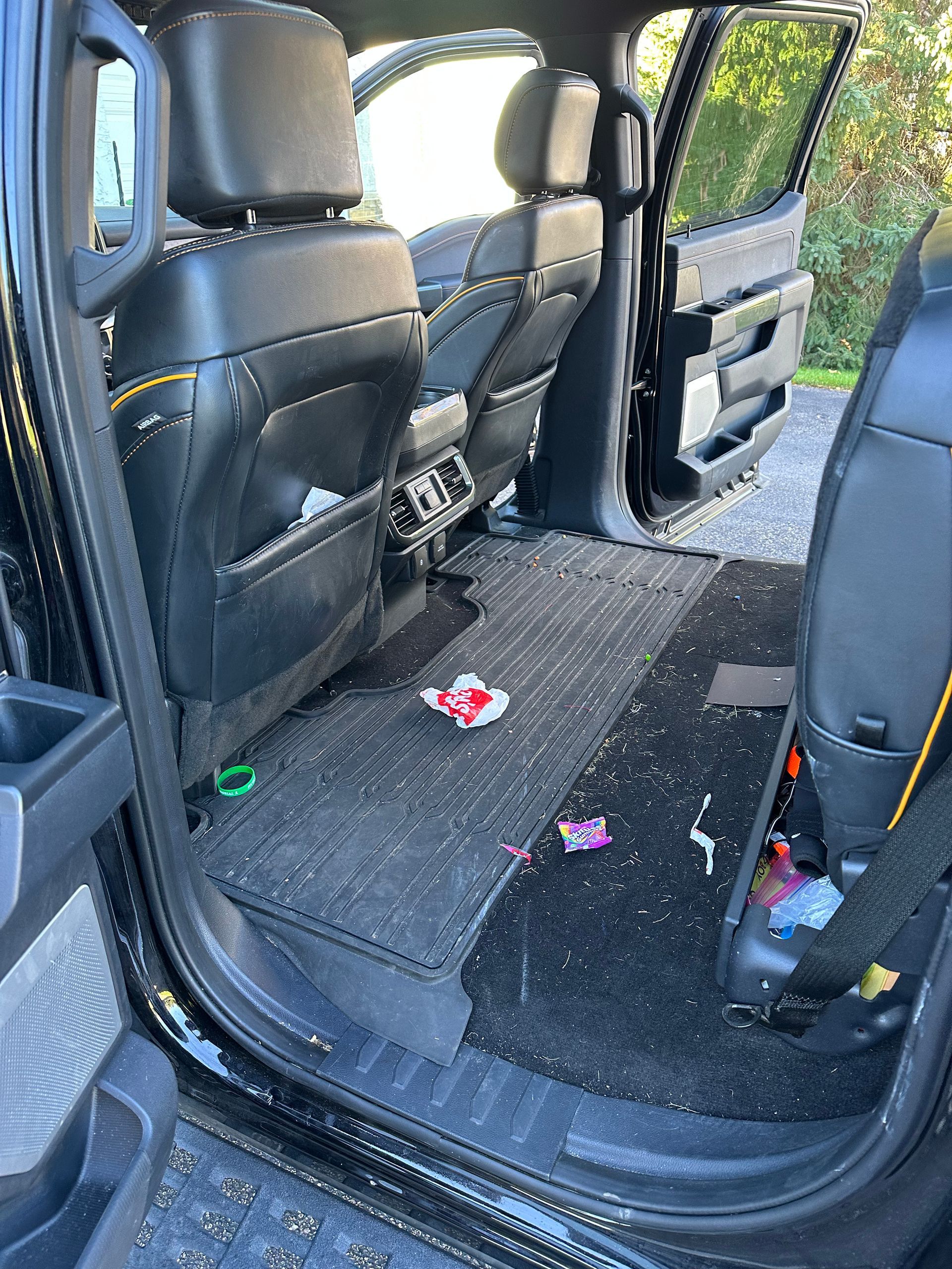 The rear interior of a truck with shattered glass covering the floor, seats, and mats from a broken window.