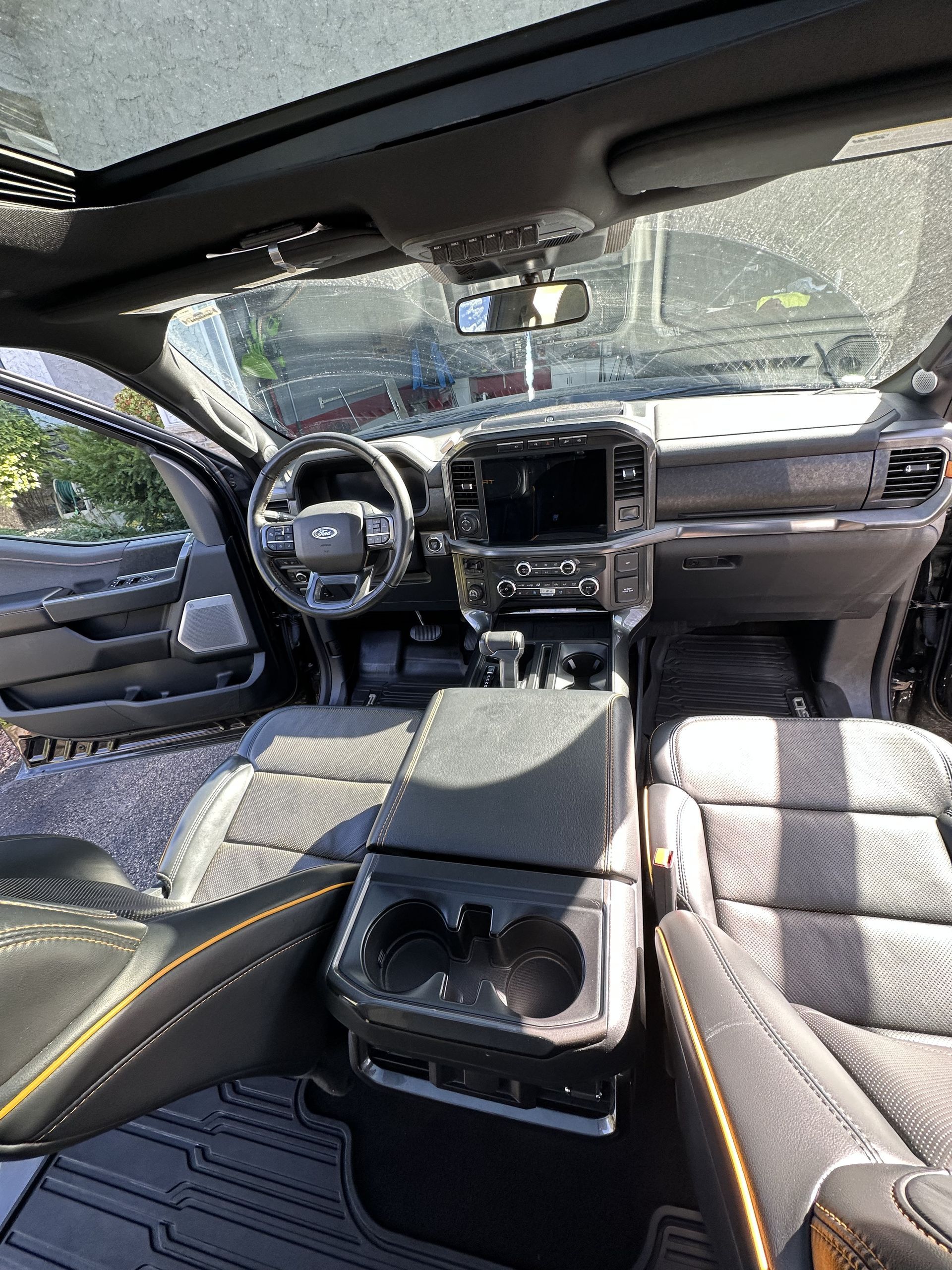 Interior view of a modern truck featuring dark leather seats with orange stitching, a center console, and a sunroof.