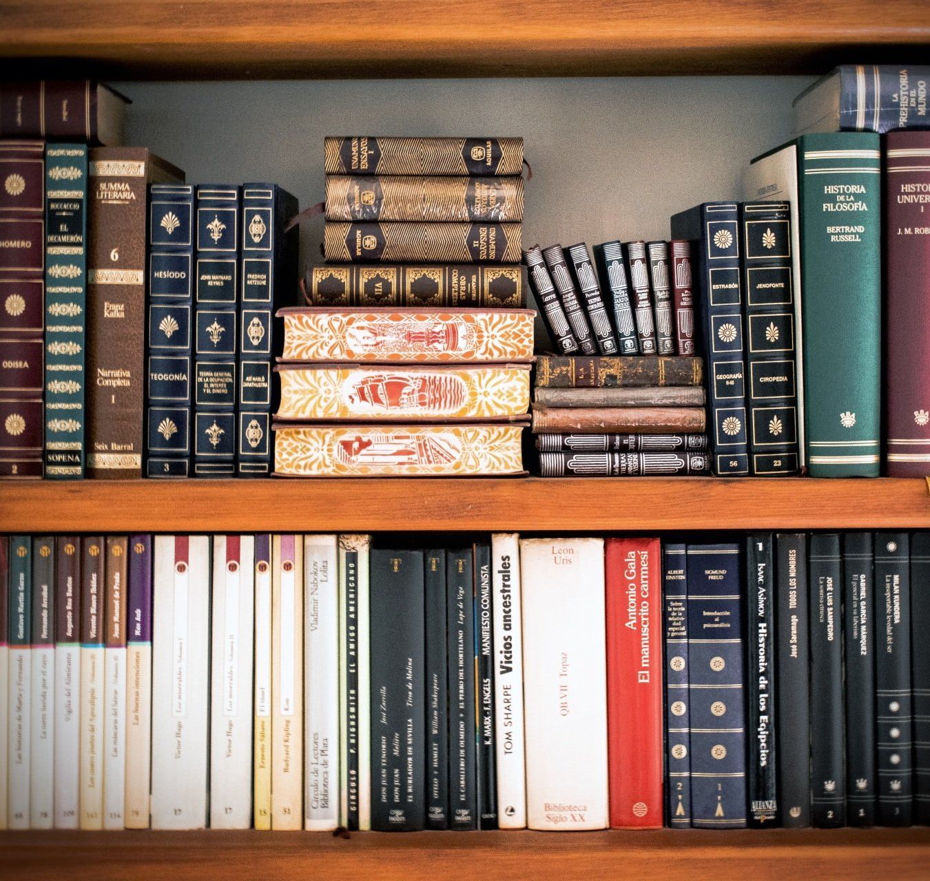 A stack of books on a shelf with one that says ' asimov ' on it