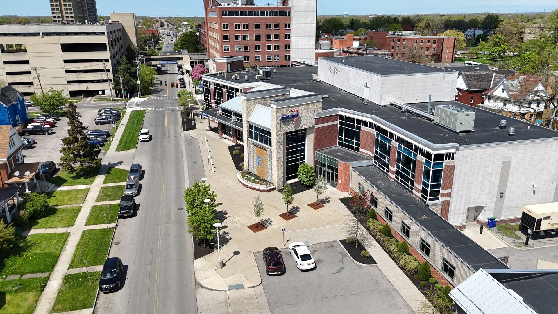 Aerial view of a downtown street with cars, trees, and modern buildings on a sunny day