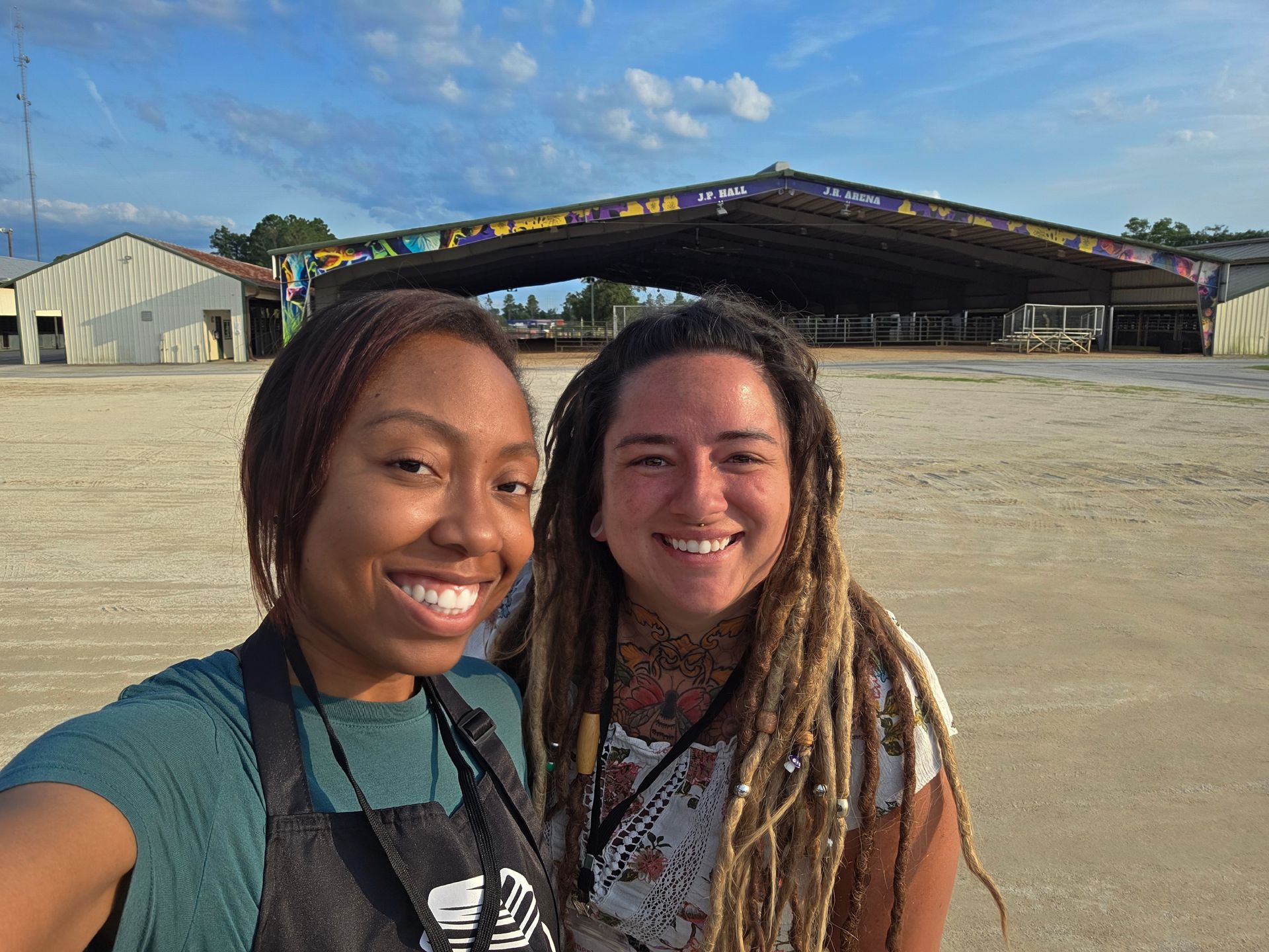 Two women with dreadlocks are posing for a picture in front of a building.