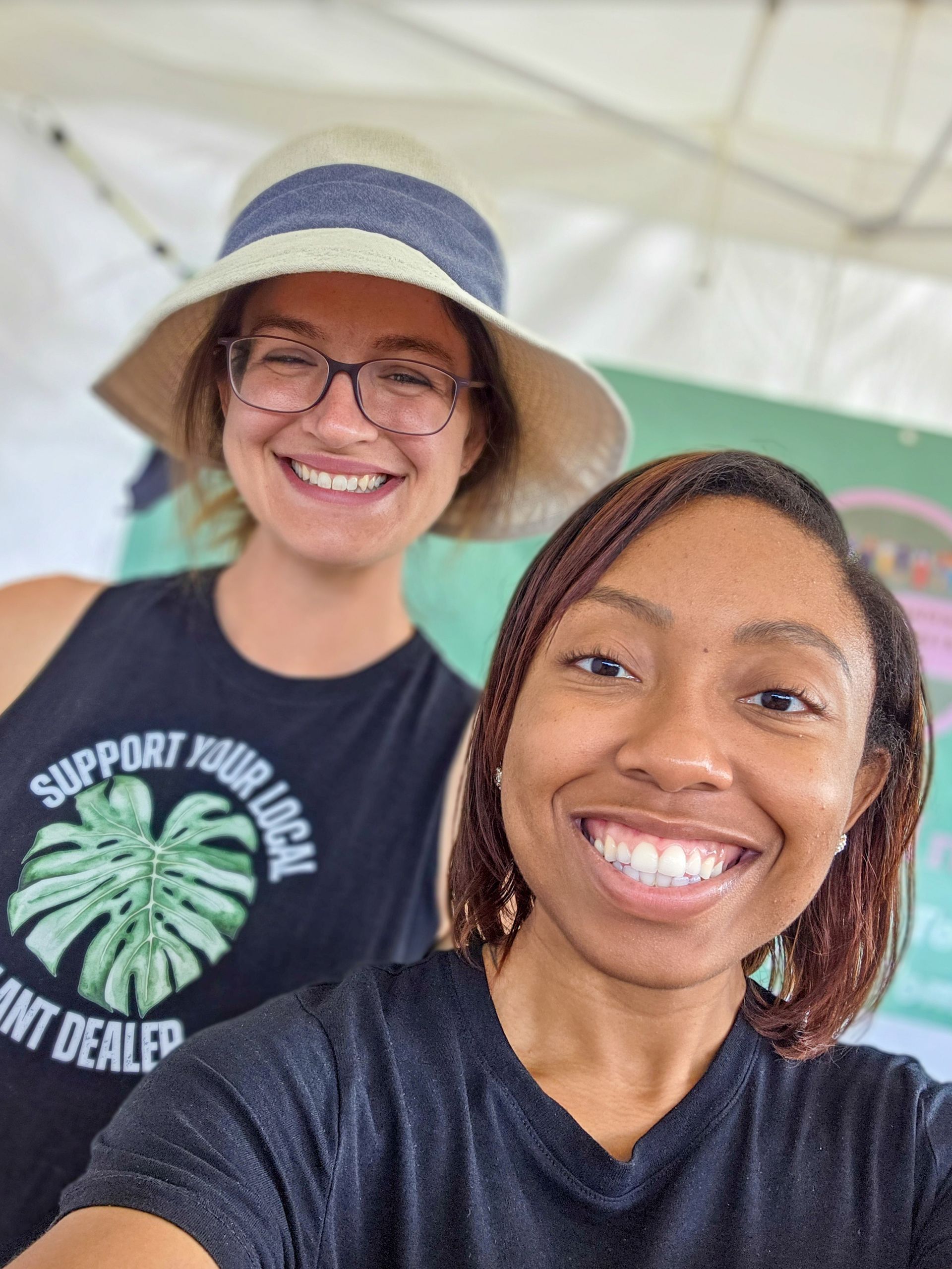 Two women are posing for a picture and one of them is wearing a shirt that says support your local plant dealer.