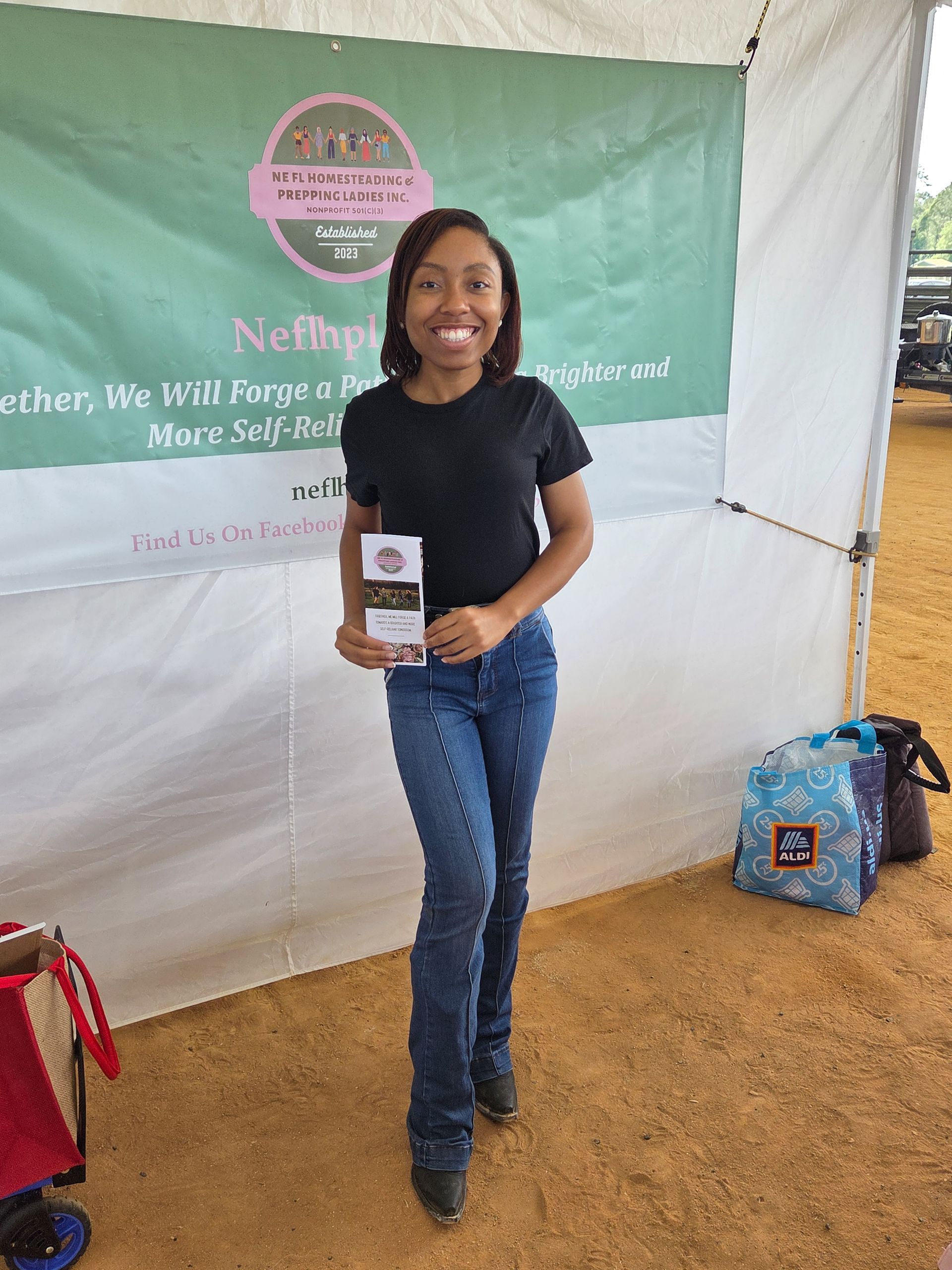 A young woman is standing in front of a tent holding a piece of paper.