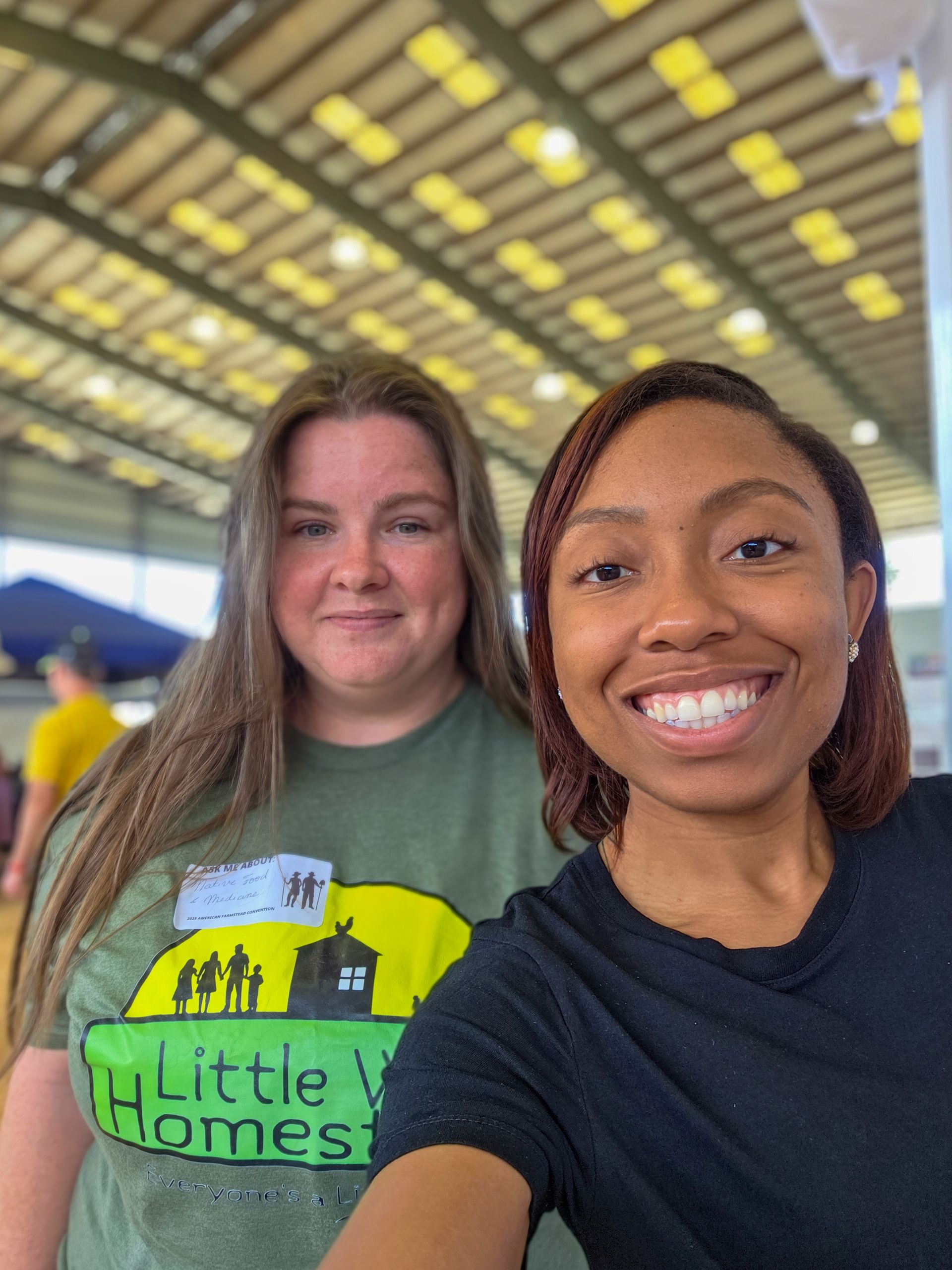 Two women are posing for a picture and one of them is wearing a little homes shirt.