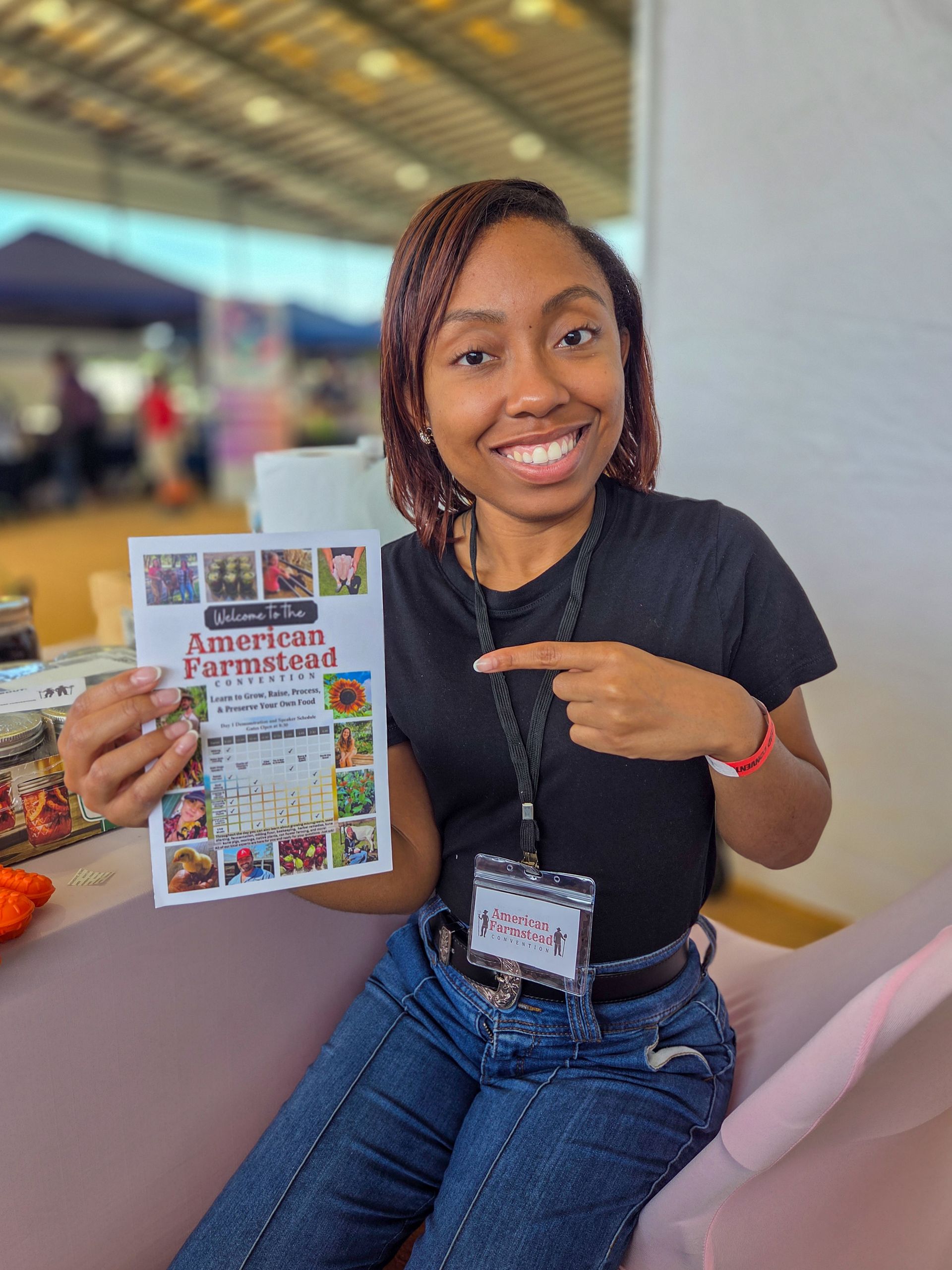 A woman is sitting on a couch holding a book and pointing at it.