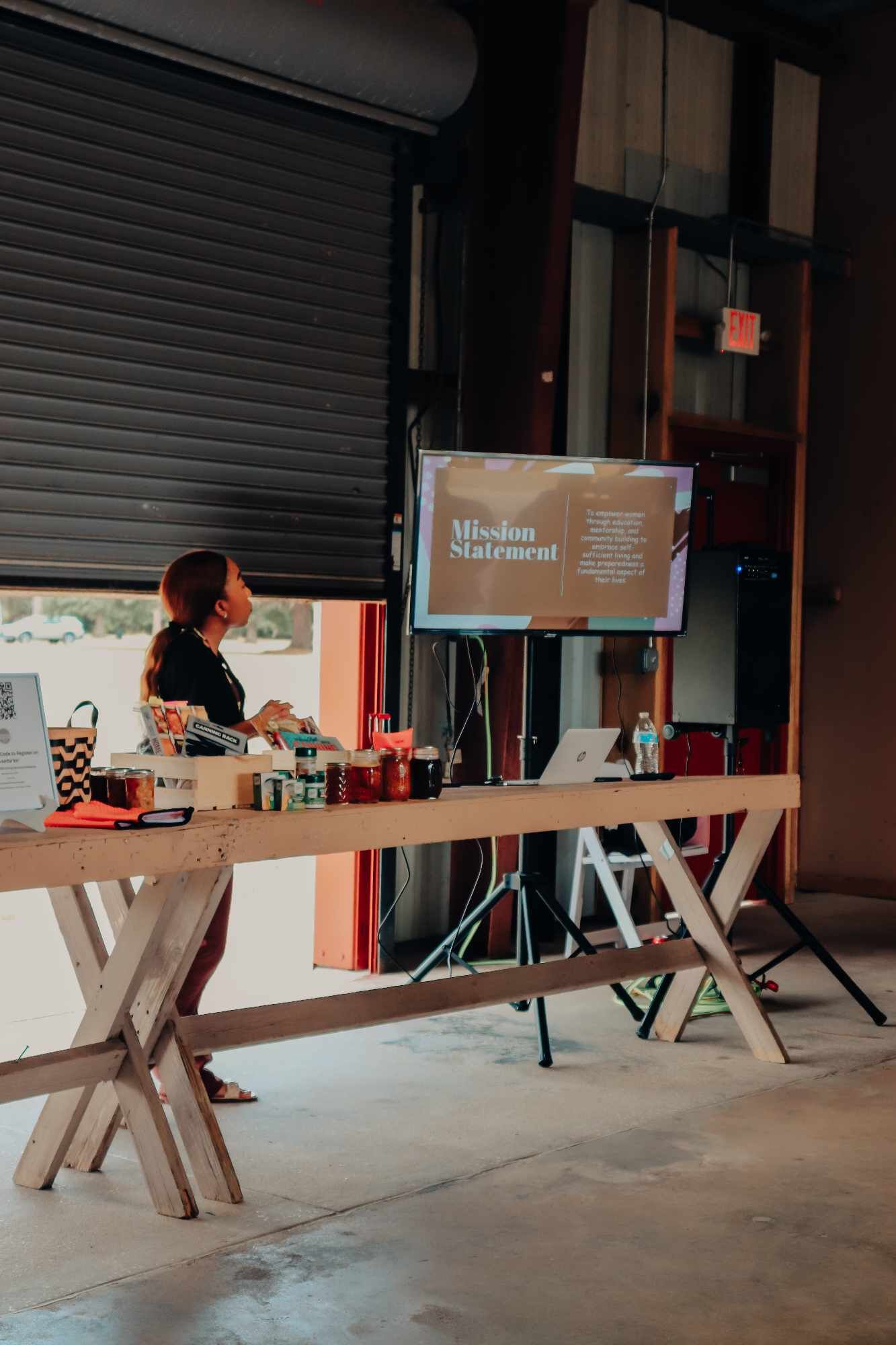A woman is sitting at a wooden table giving a presentation.