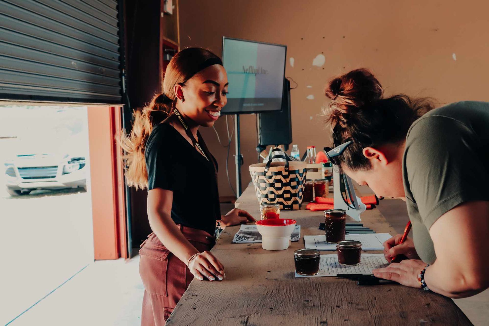 Two women are standing at a table writing on a piece of paper.