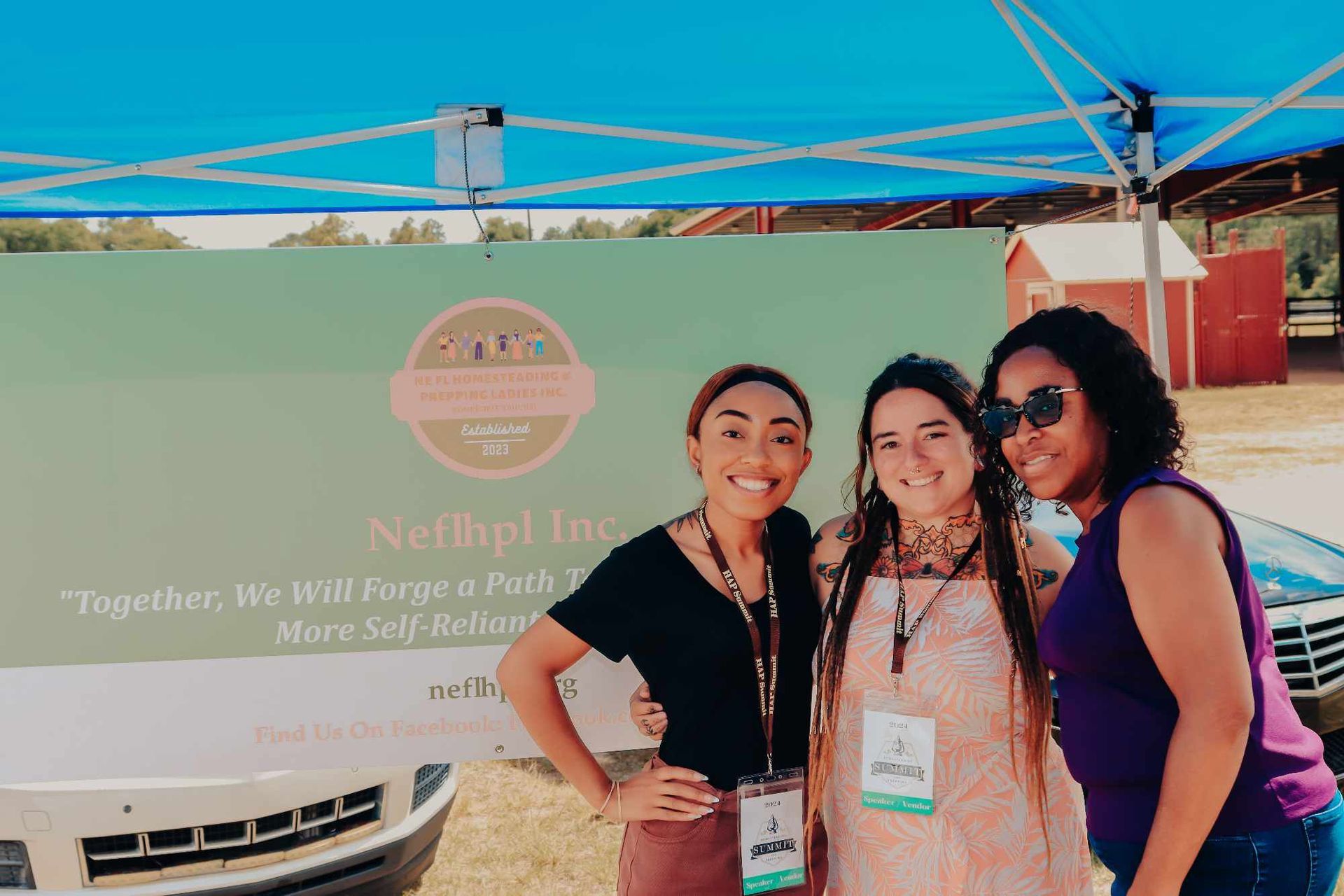 Three women are posing for a picture in front of a tent.