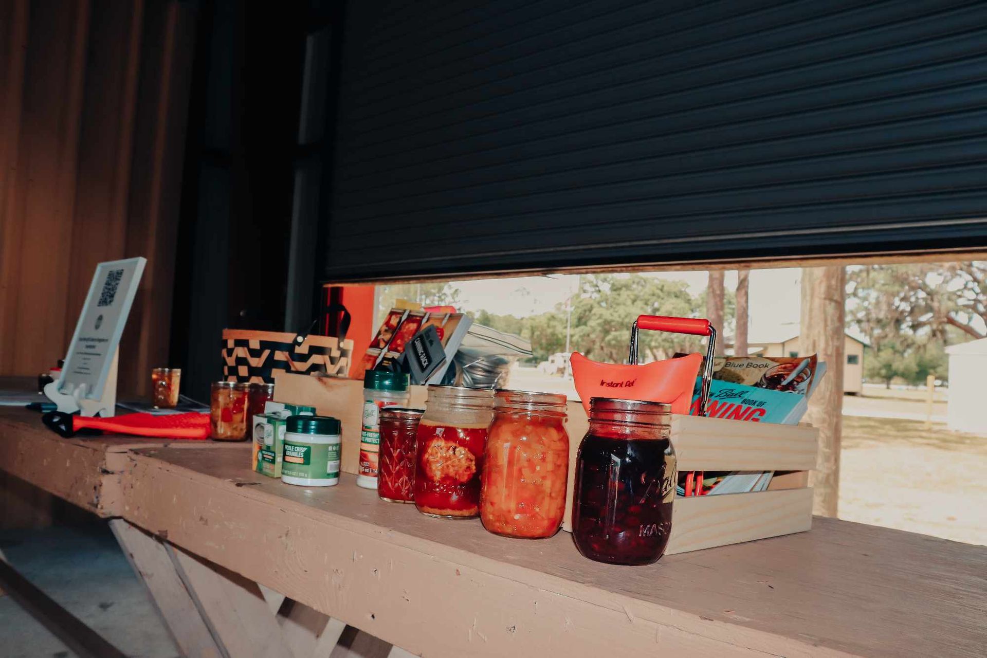 A wooden table topped with jars of food and a crate of food.