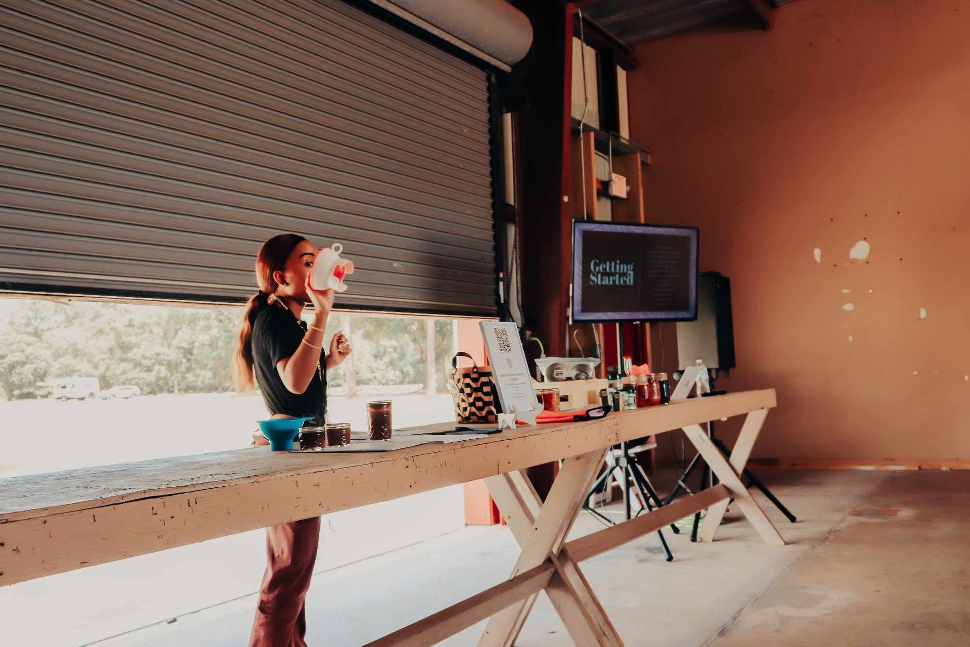 A woman is standing at a table in front of a garage door.