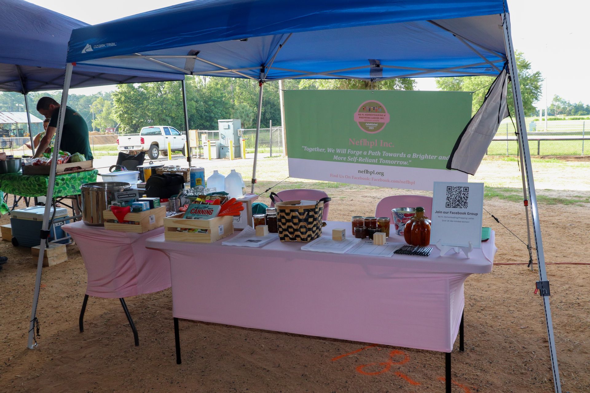 A man is standing behind a table under a tent.