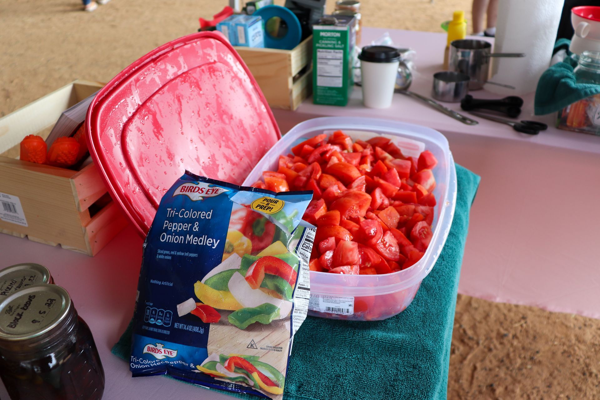 A plastic container filled with chopped tomatoes next to a bag of food