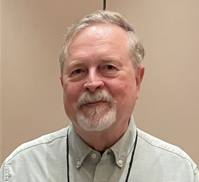 A man with a beard is wearing a lanyard around his neck.