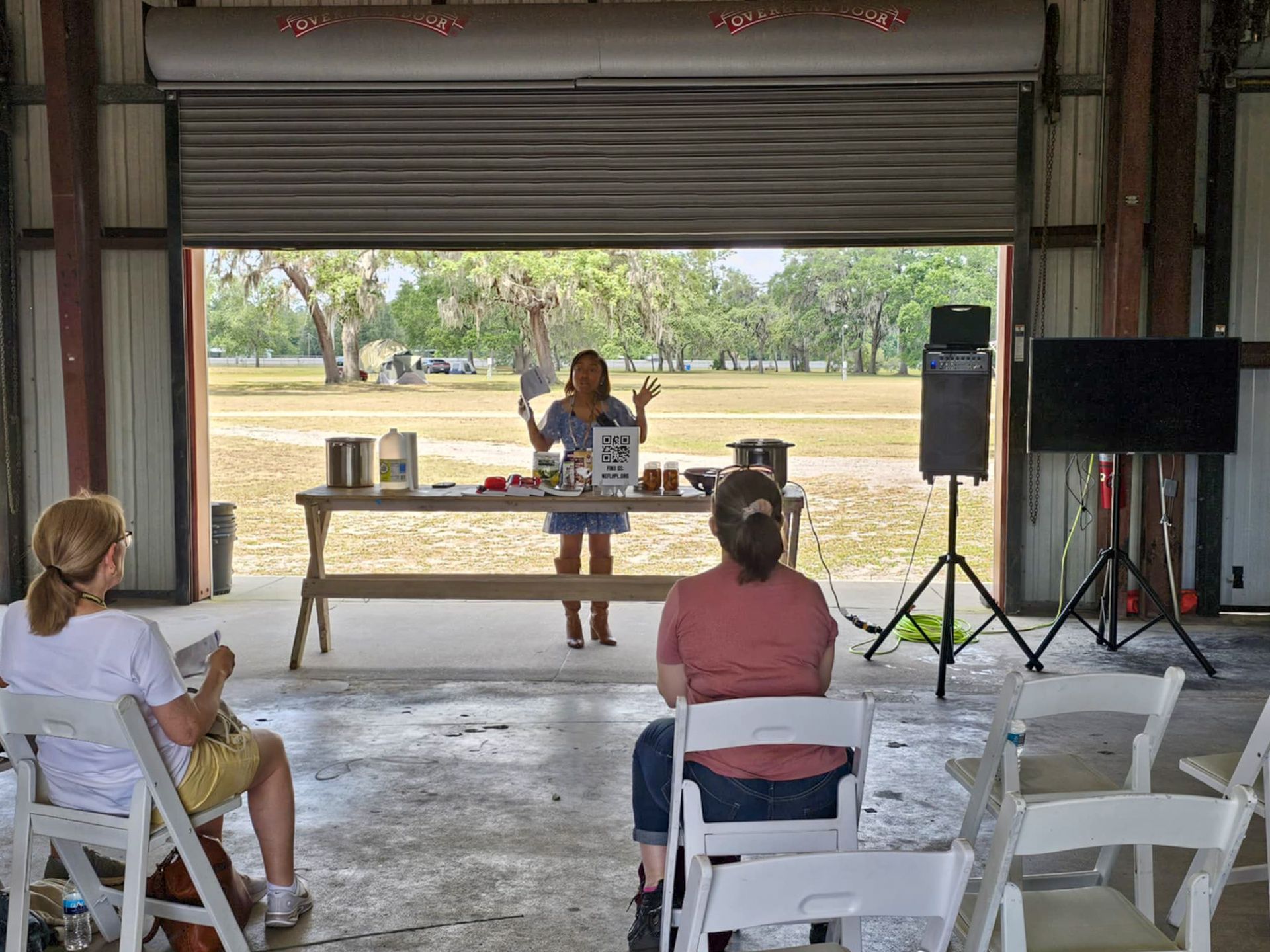A woman is giving a presentation to a group of people in a barn.