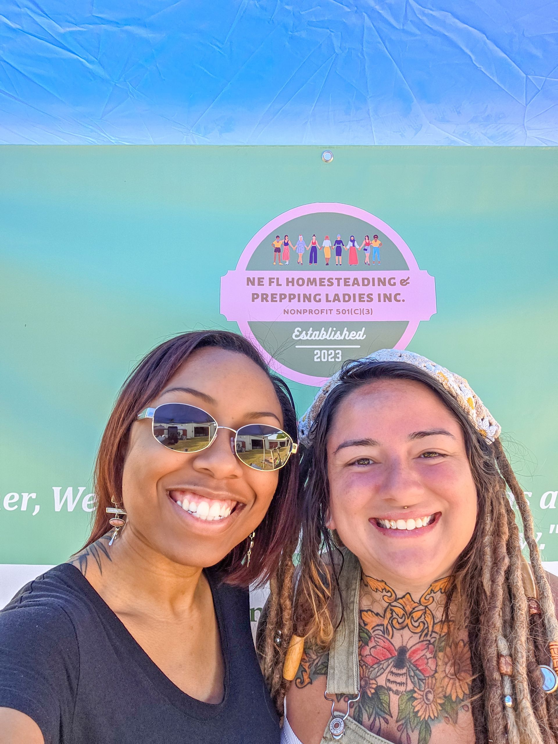 Two women are posing for a picture in front of a green wall.