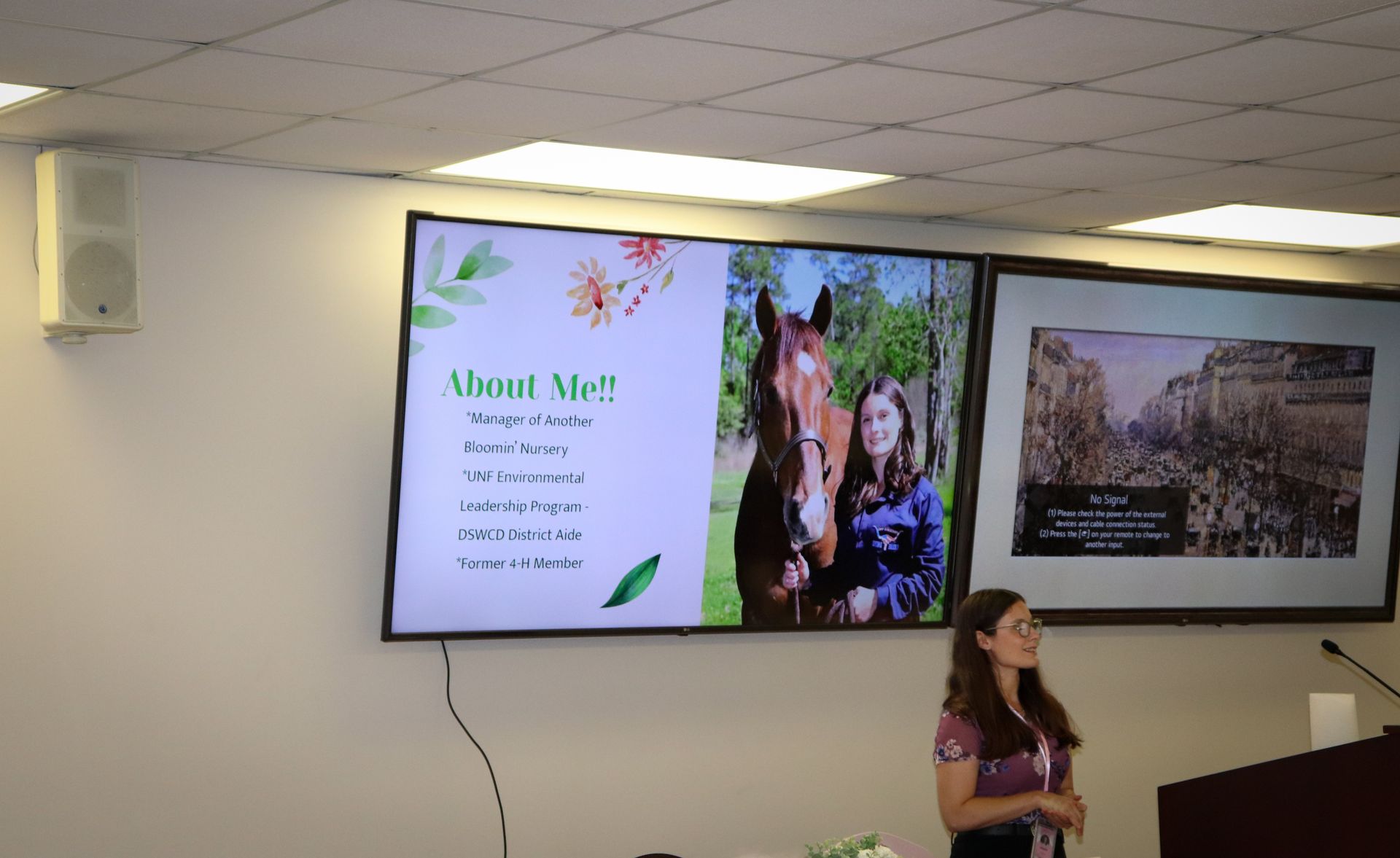 A woman is standing in front of a screen that says about me