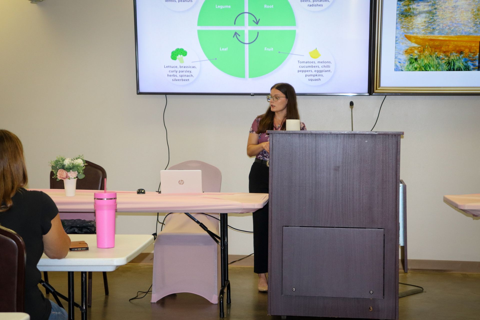 A woman is standing at a podium giving a presentation to a group of people.