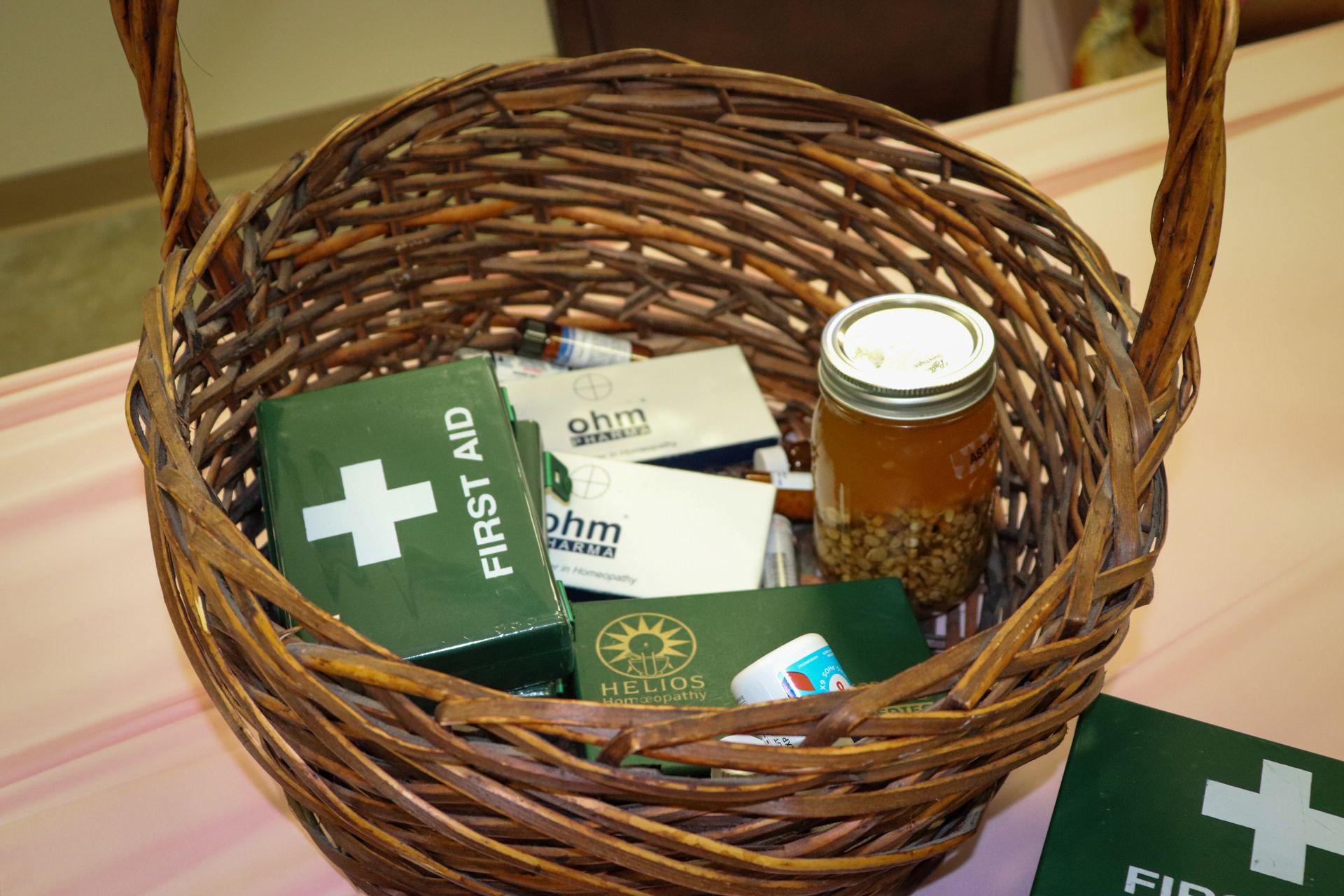 A wicker basket filled with first aid supplies and a jar of honey