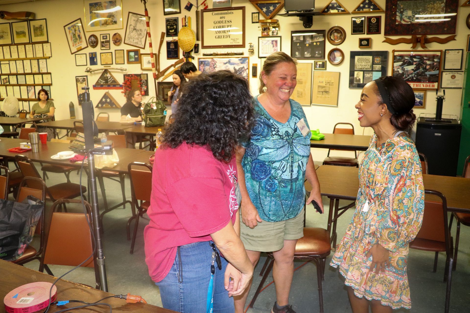 Three women are standing in a room talking to each other