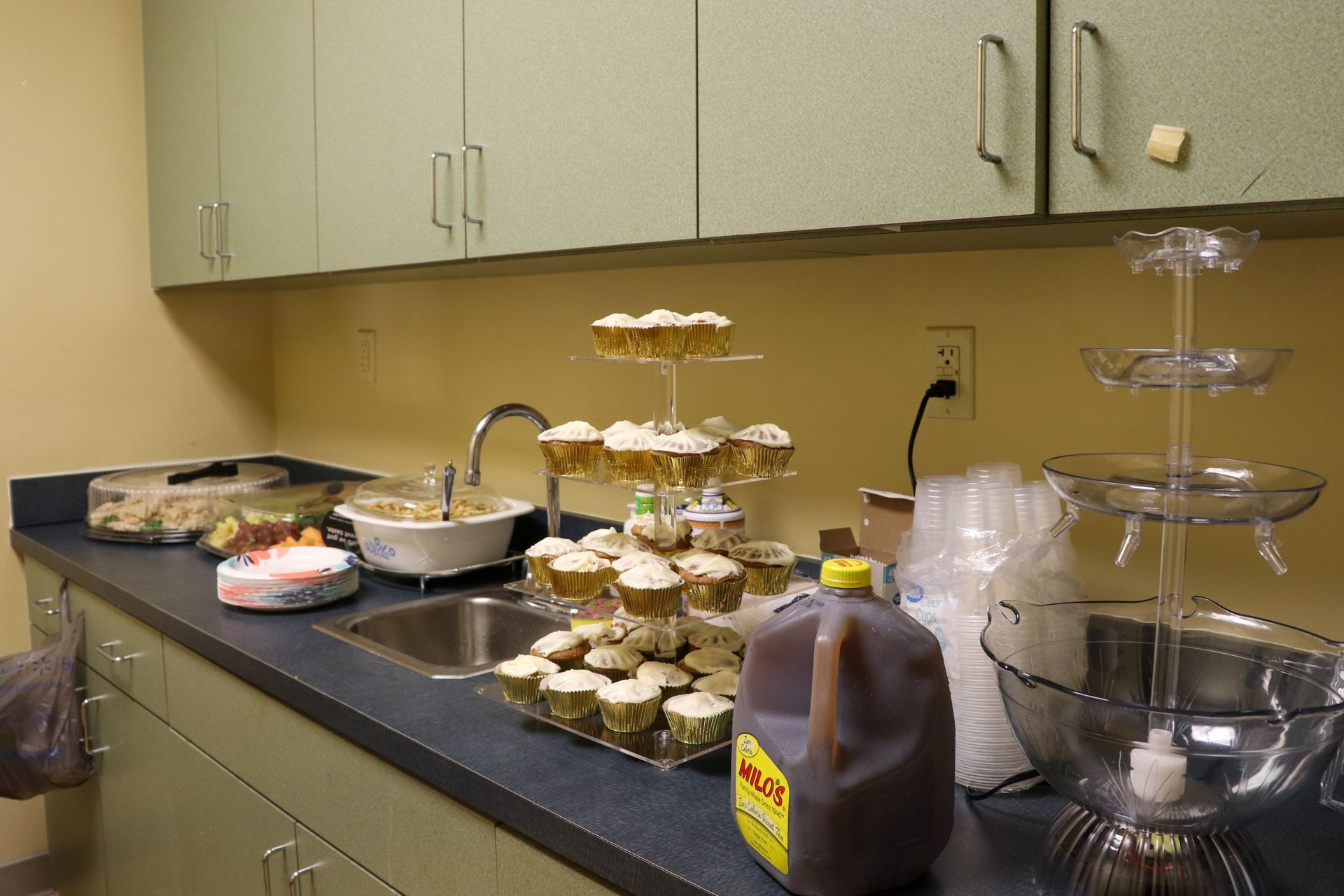 A kitchen counter with cupcakes and a gallon of milk