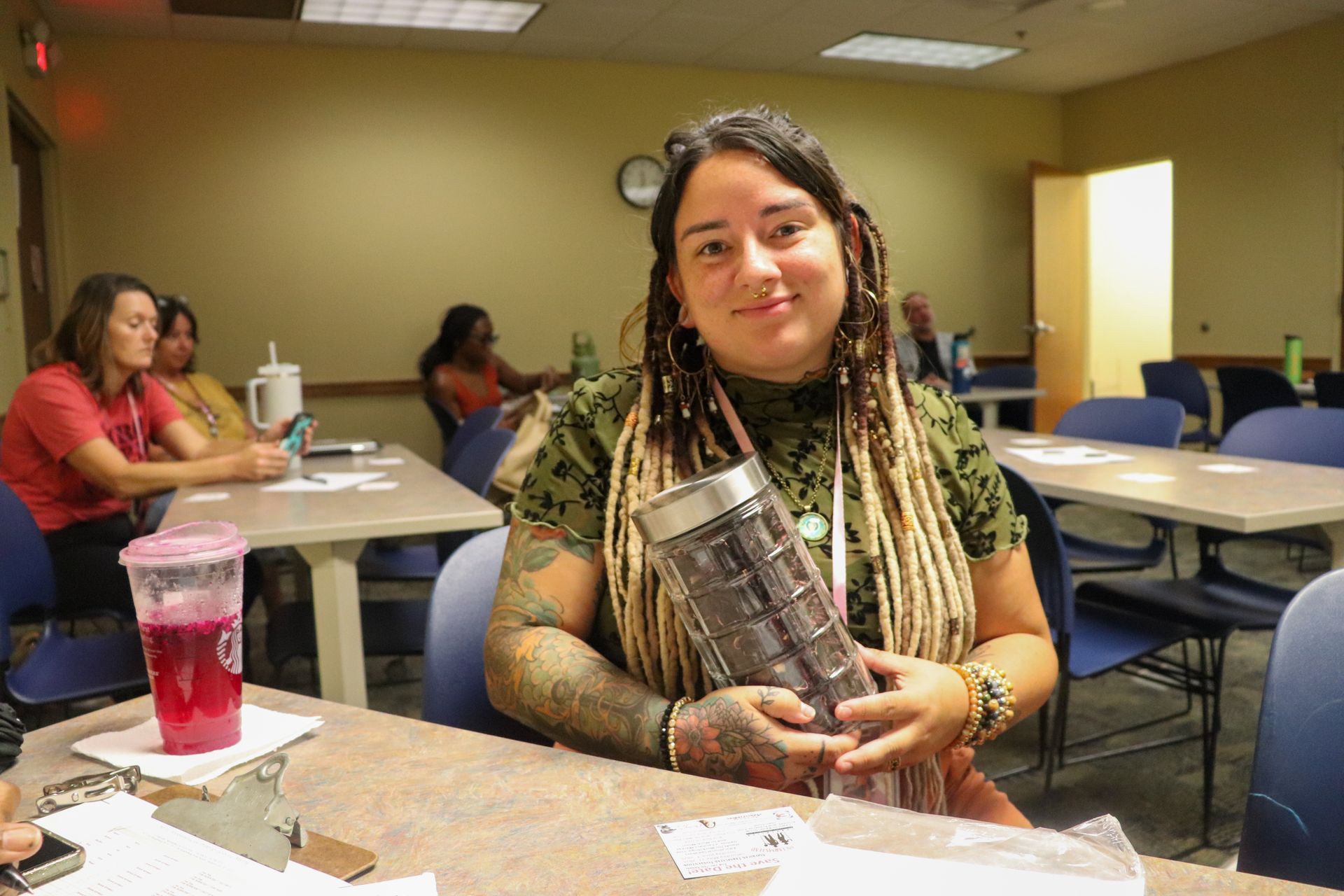 A woman is sitting at a table holding a container.