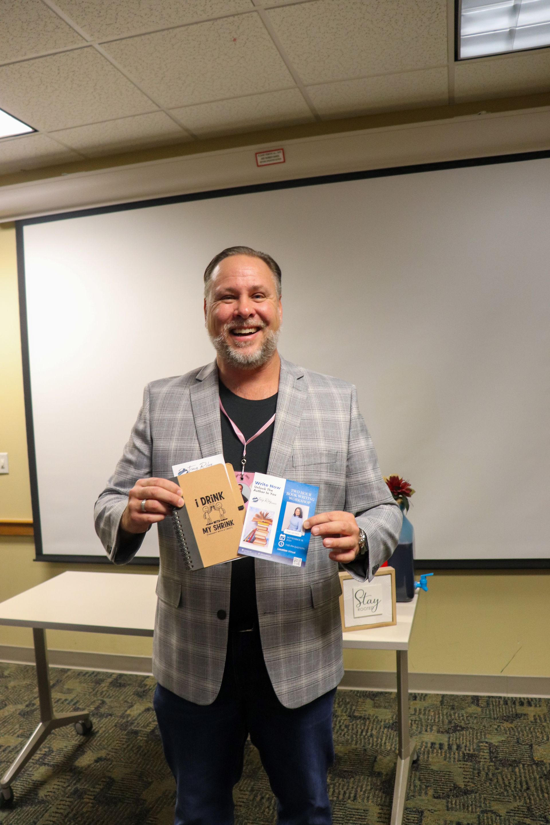 A man in a suit is holding a brochure in front of a white board.
