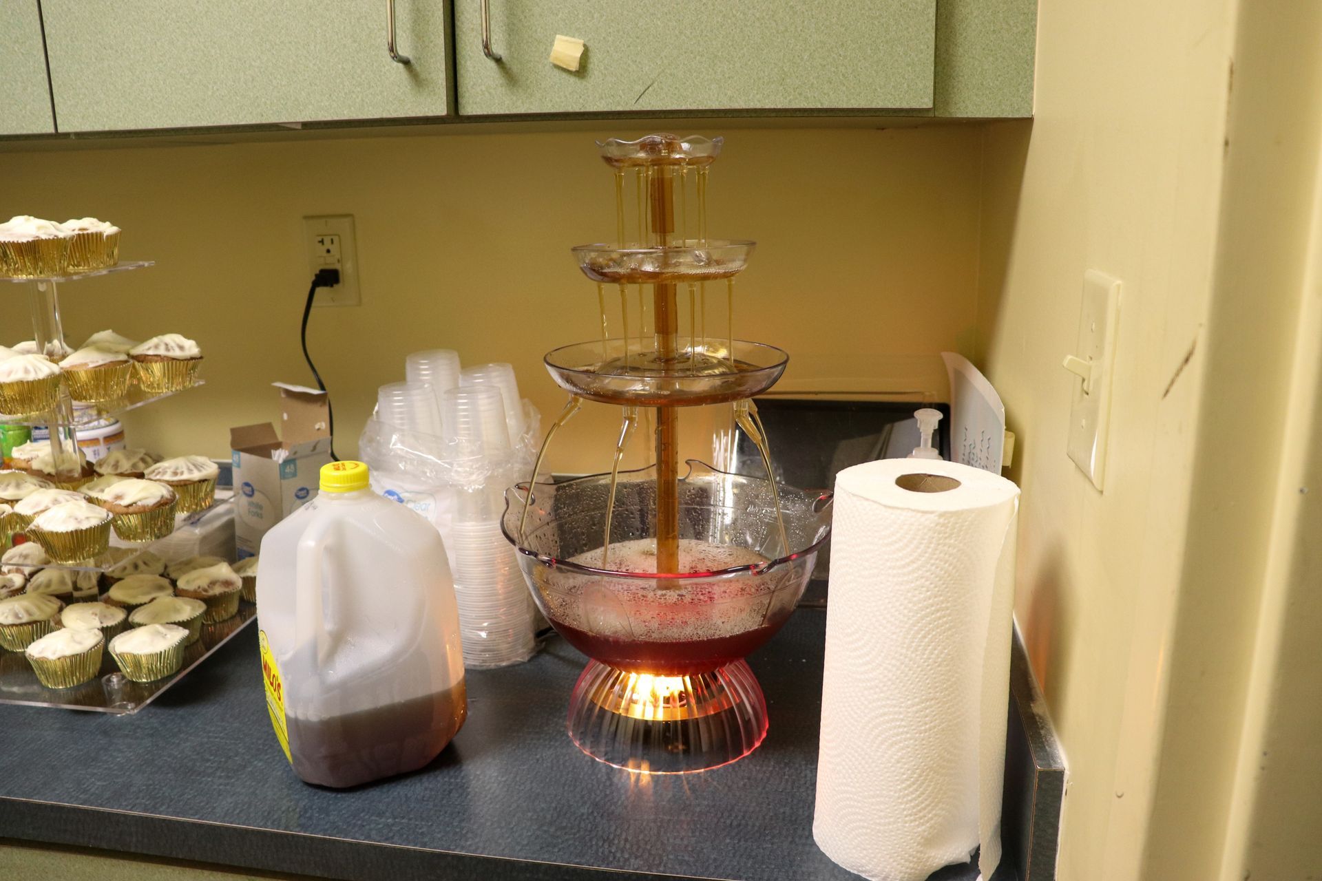 A kitchen counter with cupcakes and a paper towel roll